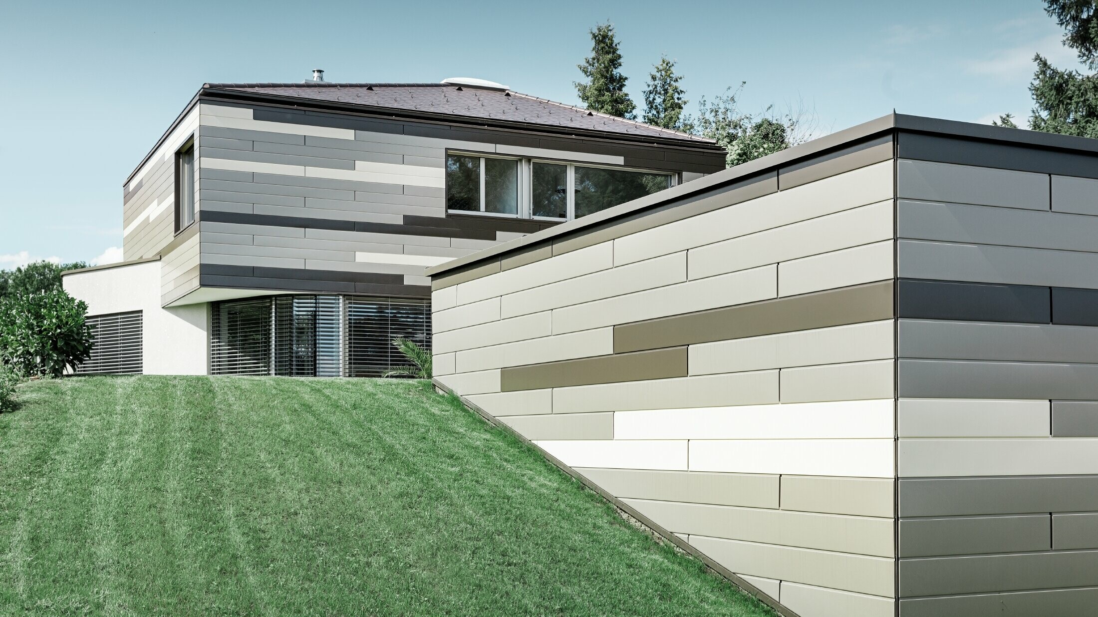 Moderne enfamiliehus med fladt tag og overdækket terrasse med en individuel formgivet aluminiumfacade af Sidings i brun, bronze og elfenben fra PREFA