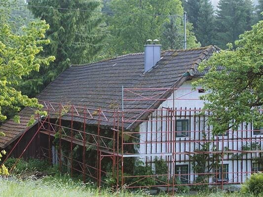 Det gamle tag på hytten lige inden renoveringen med PREFA tagspån (med stillads)