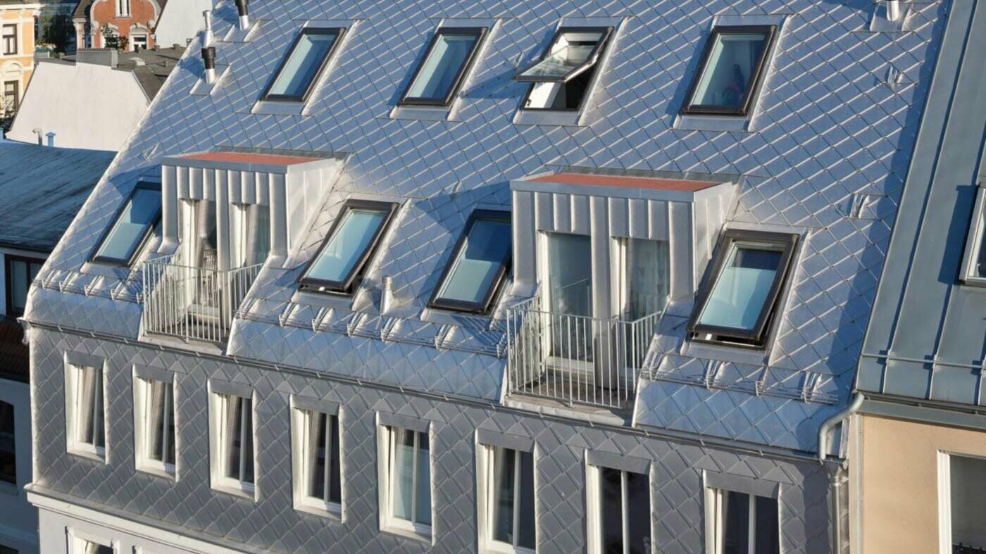 Blankt aluminiumstag med skælmønster ved udvidelse af tagetage med mange tagvinduer