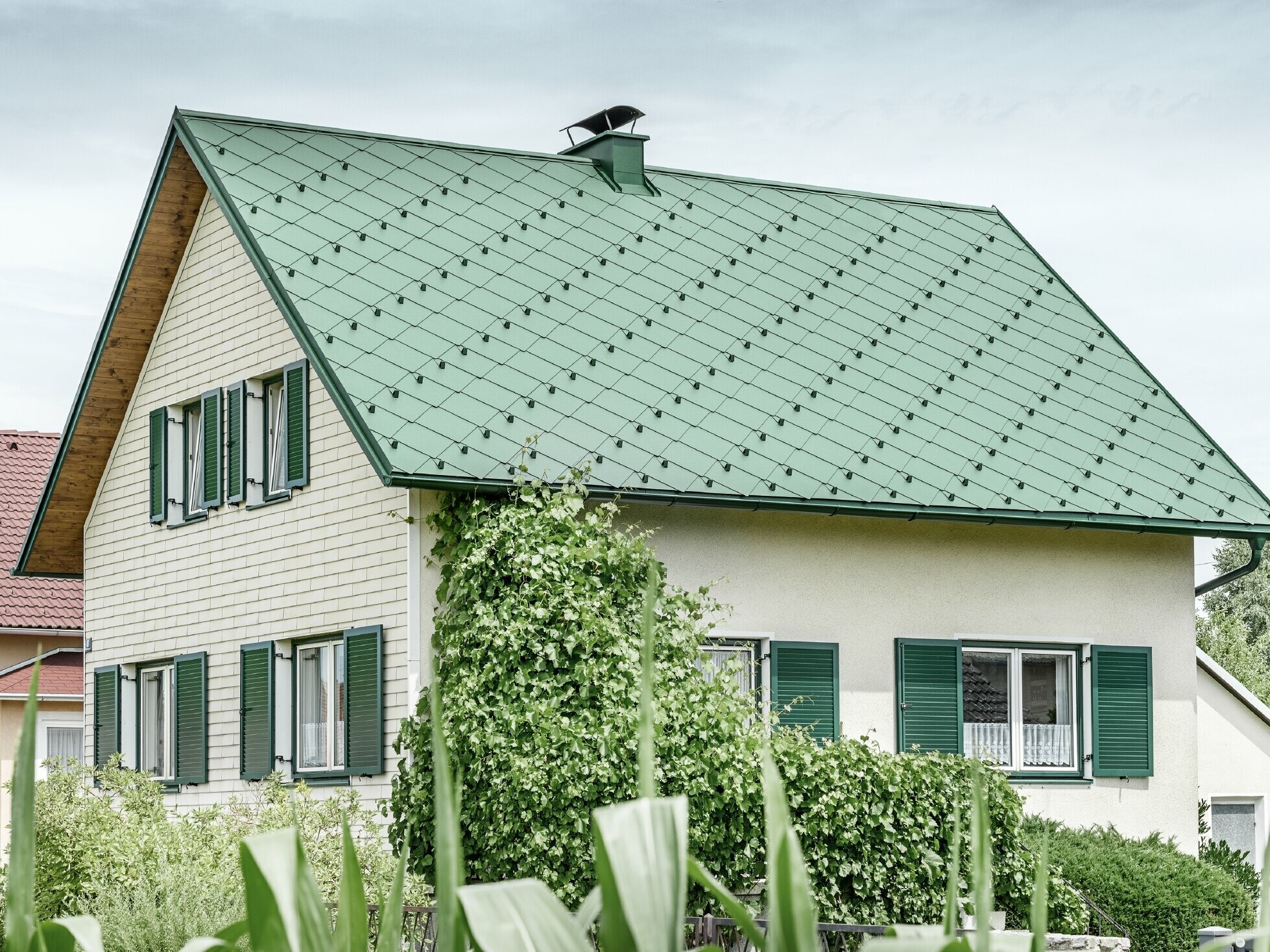 Klassisk enfamilieshus med sadeltag med en taginddækning af aluminium fra mosgrøn med grønne vinduesskodder