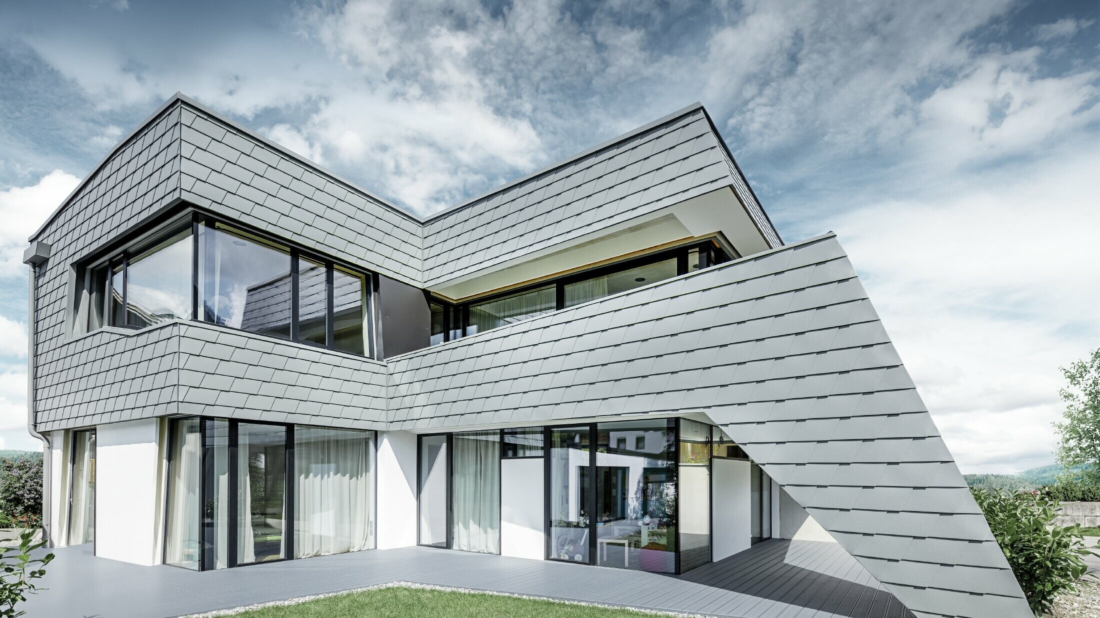 Moderne enfamiliehus med fladt tag, store vinduesflader og en vægspån-facade i lysegrå af aluminium fra PREFA