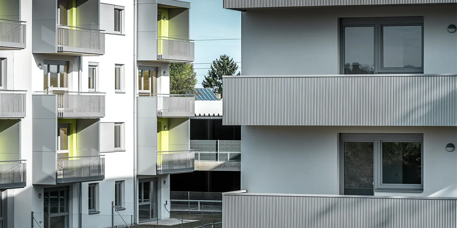 Nahaufnahme der Balkone der Glanzstoffsiedlung in St. Pölten, Niederösterreich. Die Balkone sind mit dem langlebigen PREFA Zackenprofil in der Farbe Silbermetallic verkleidet. Die Beschattung zeigt deutlich, wie sich das Zackenprofil durch Sonneneinstrahlung optisch verändert.
