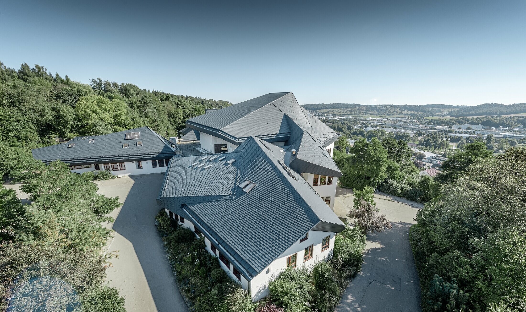 Waldorfschule i Heidenheim med nyt saneret tag. Den store tagflade med mange vinkler og taghældninger blev dækket med PREFA tagspån i antracit