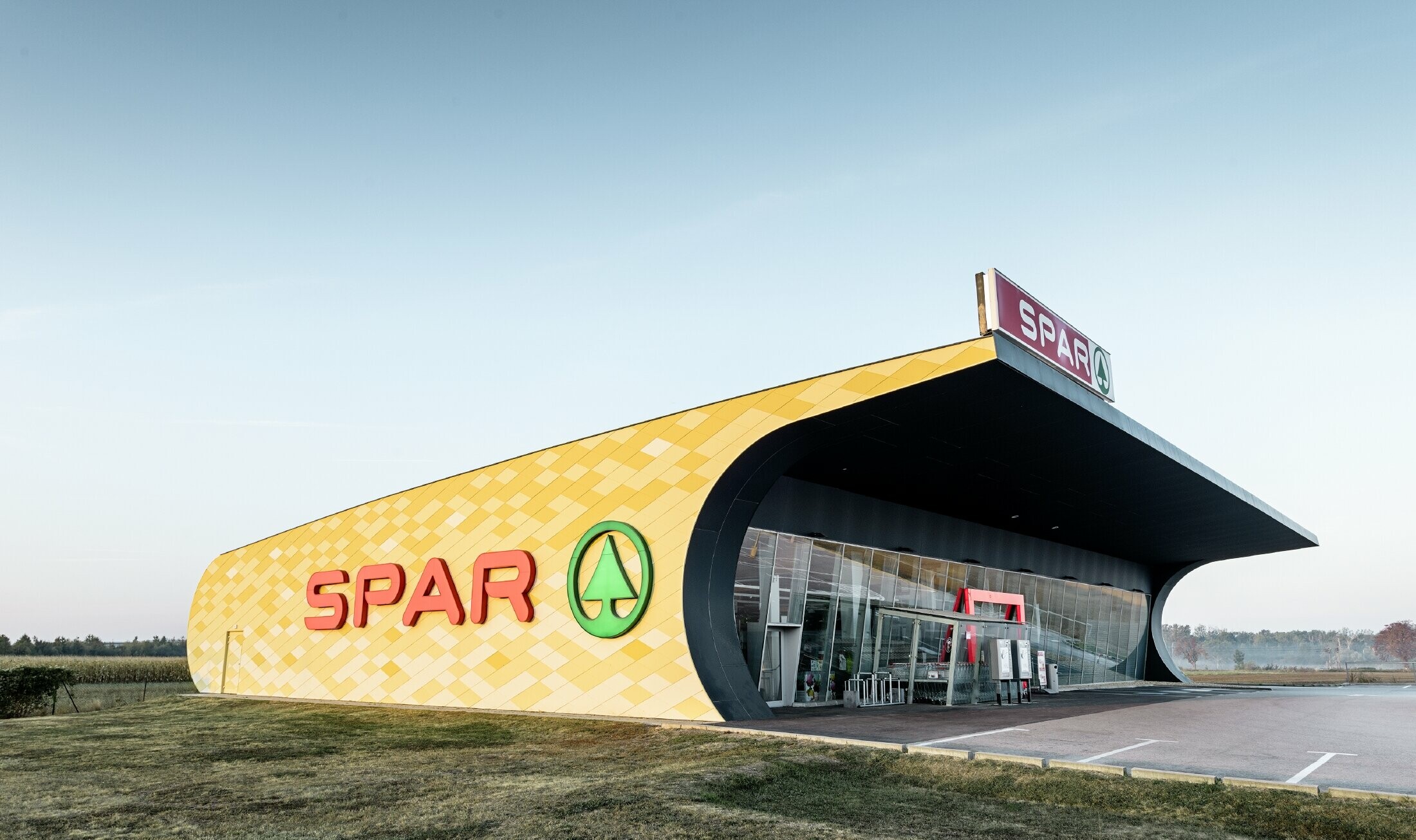 Spar-filial med en aluminiumfacade i gul-orange firkanter og Spar Logo