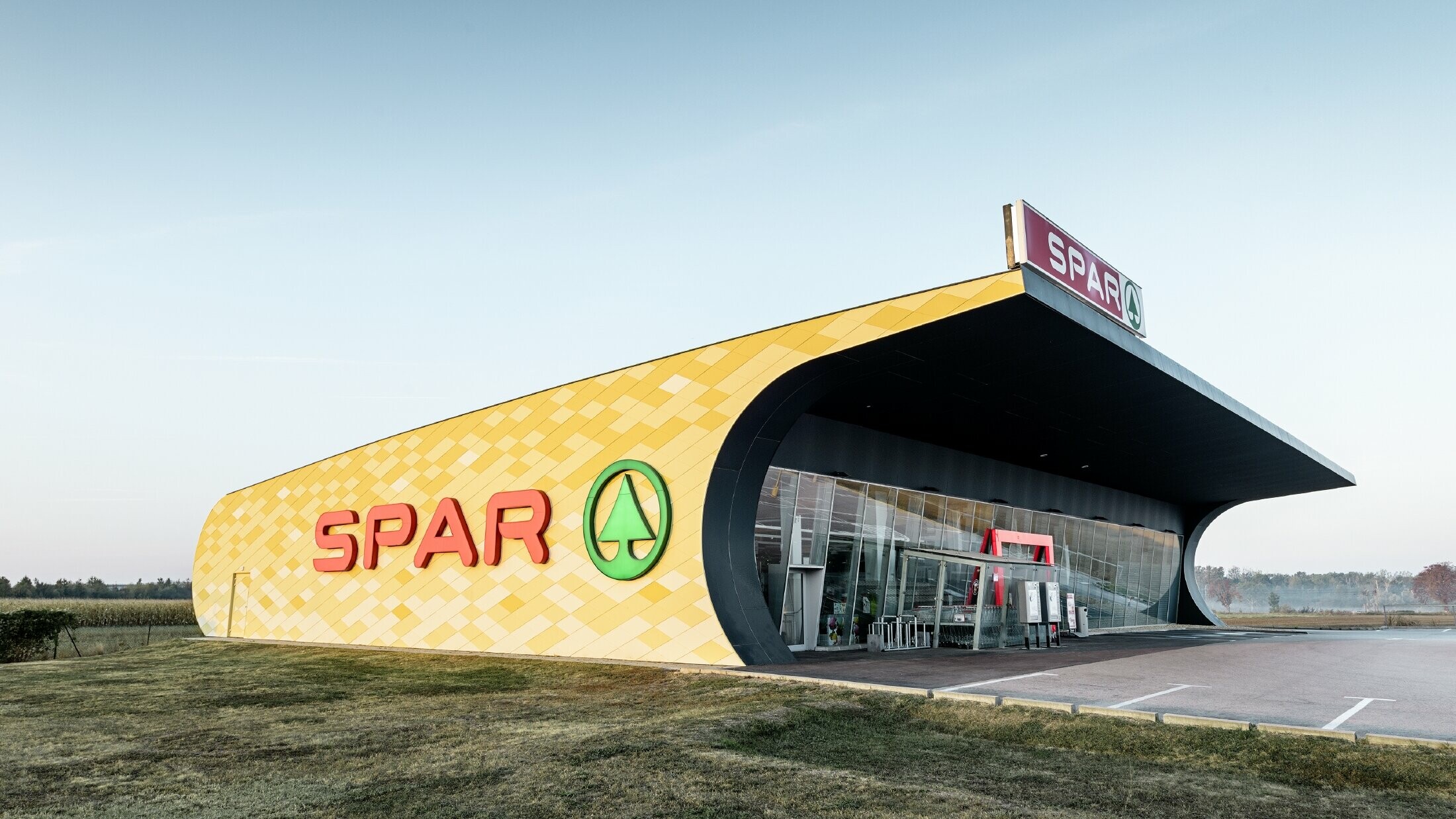 Spar-filial med en aluminiumfacade i gul-orange firkanter og Spar Logo