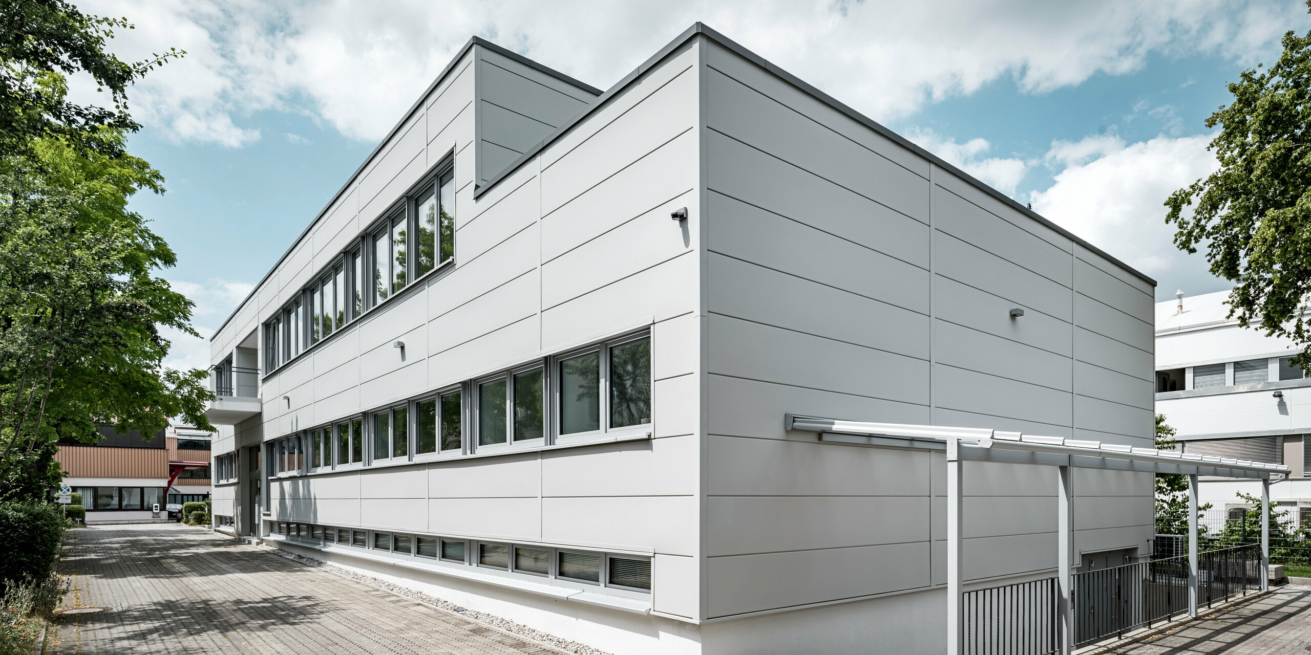 Großformatige PREFA Sidings umhüllen ein Firmengebäude in Oberschleißheim (Deutschland). Die extrabreiten Fassadenelemente aus Aluminium sind in der Farbe Prefaweiß gehalten.