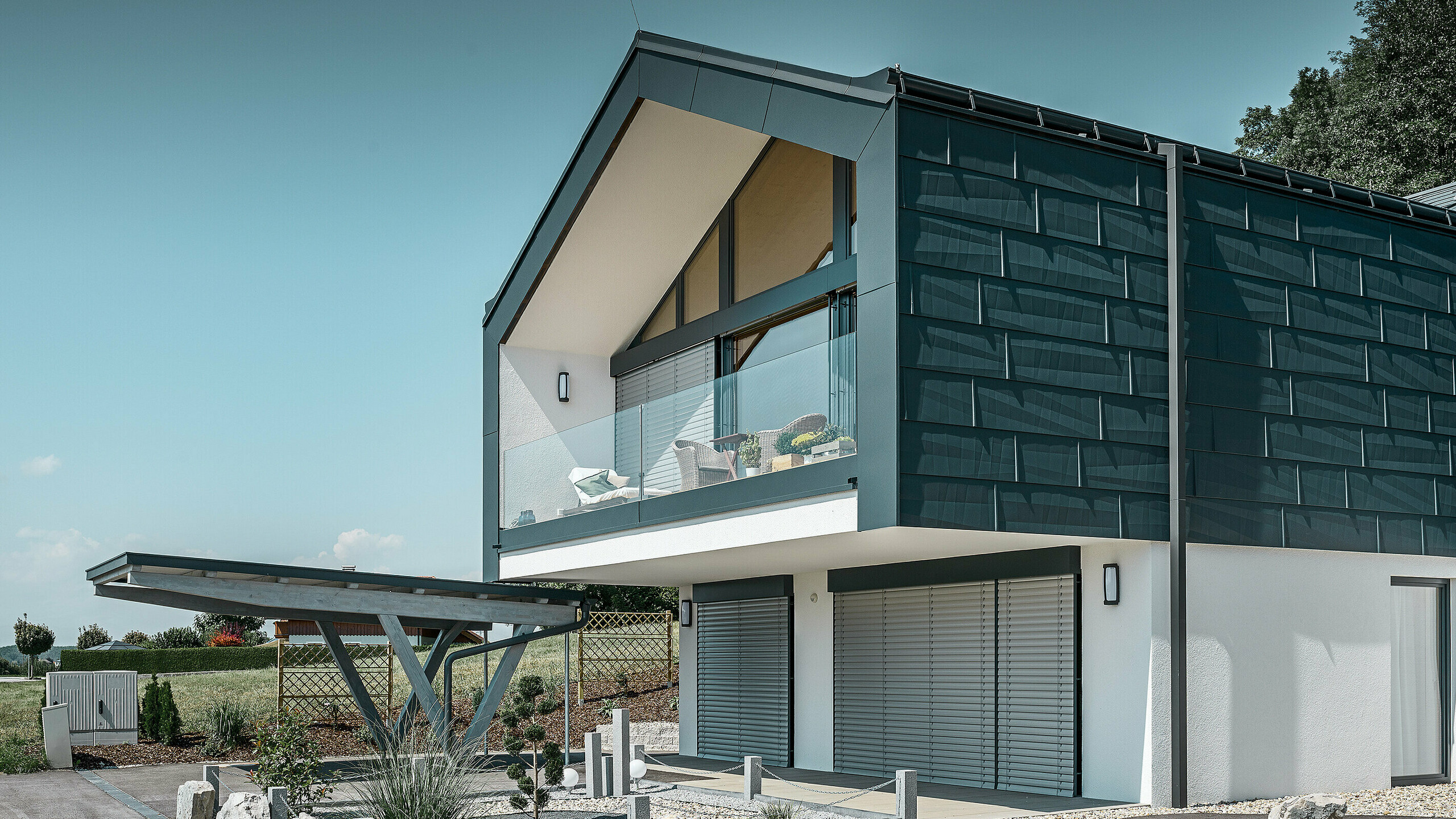 Facadebeklædning af øverste etage med PREFA facadepaneler FX.12 i P.10 antracit. Her er det robuste PREFA kvadratrør anvendt som nedløbsrør.