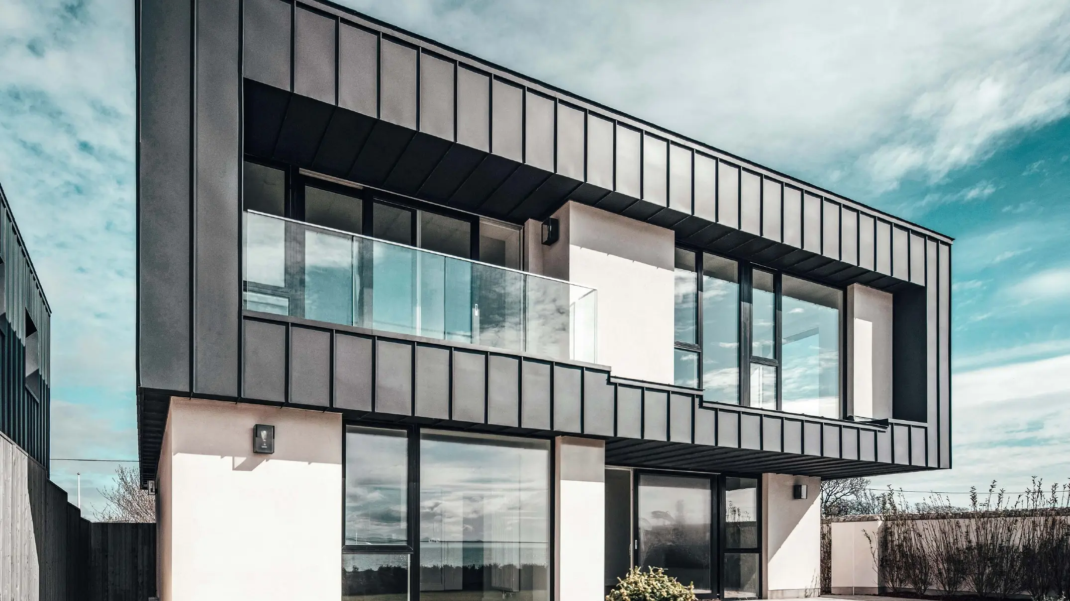 Moderne rækkehus med fladt tag, facaden på øverste etage er udformet med en vinkelstående falsfacade udført i PREFALZ i antracit.
