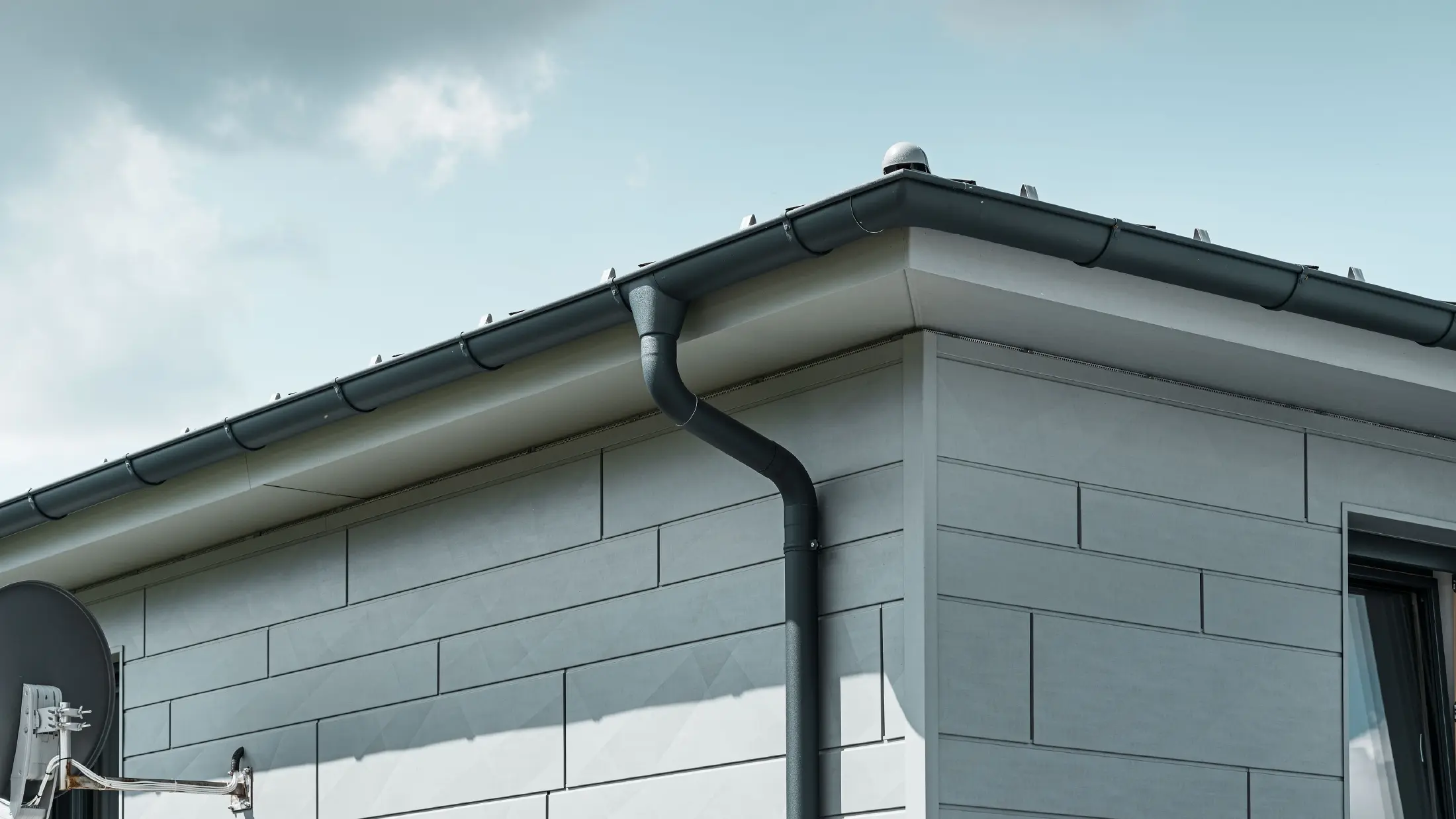 Tagunderlag med PREFA-tagrende, tudstykke til rende og nedløbsrør i antracit med PREFA Siding.X-facade i patinagrå