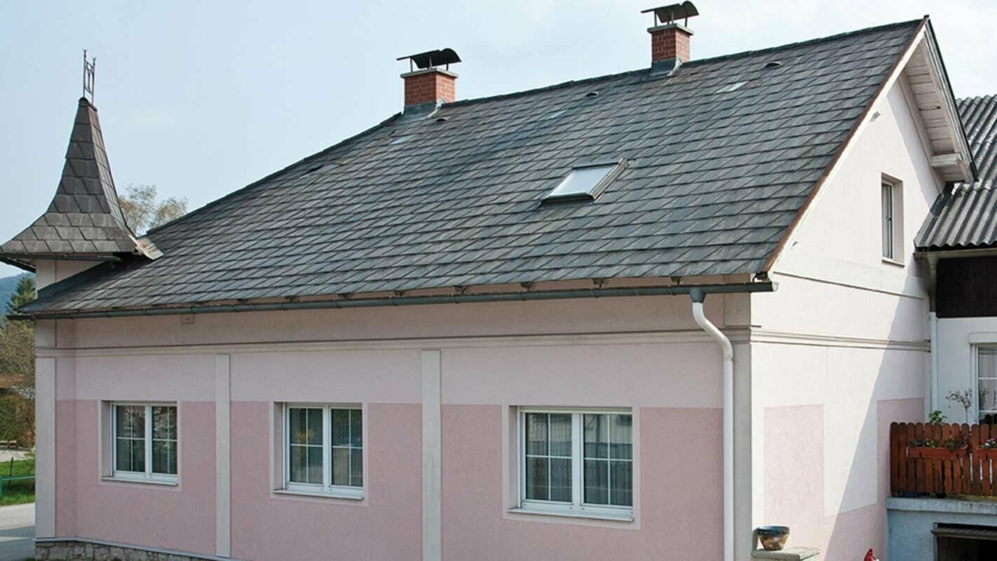 Hus før tagrenovering med PREFA tagplader i Østrig - tidligere beklædt med Eternit/fibercement samt tårne og lyserød facade