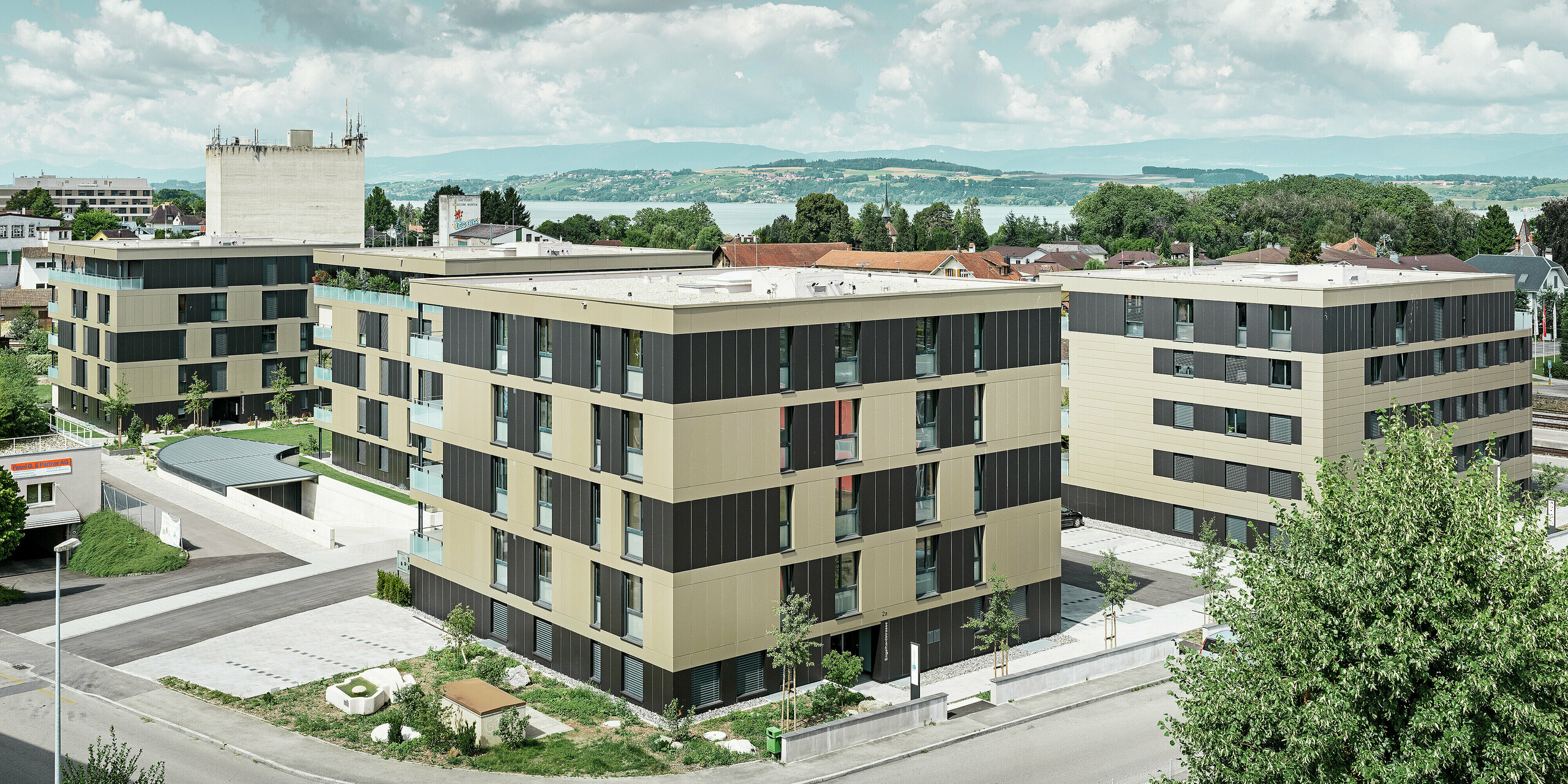 Die markante Architektur der Wohnanlage in Murten (CH) wird durch den Einsatz von PREFABOND Aluminium Verbundplatten in den Farben Bronze und Schwarzgrau perfekt umhüllt. Die langlebige und pflegeleichte Blechfassade schützt das Gebäude vor äußeren Witterungseinflüssen und sorgt gleichzeitig für eine moderne und elegante Ästhetik, die das gesamte Umfeld bereichert.