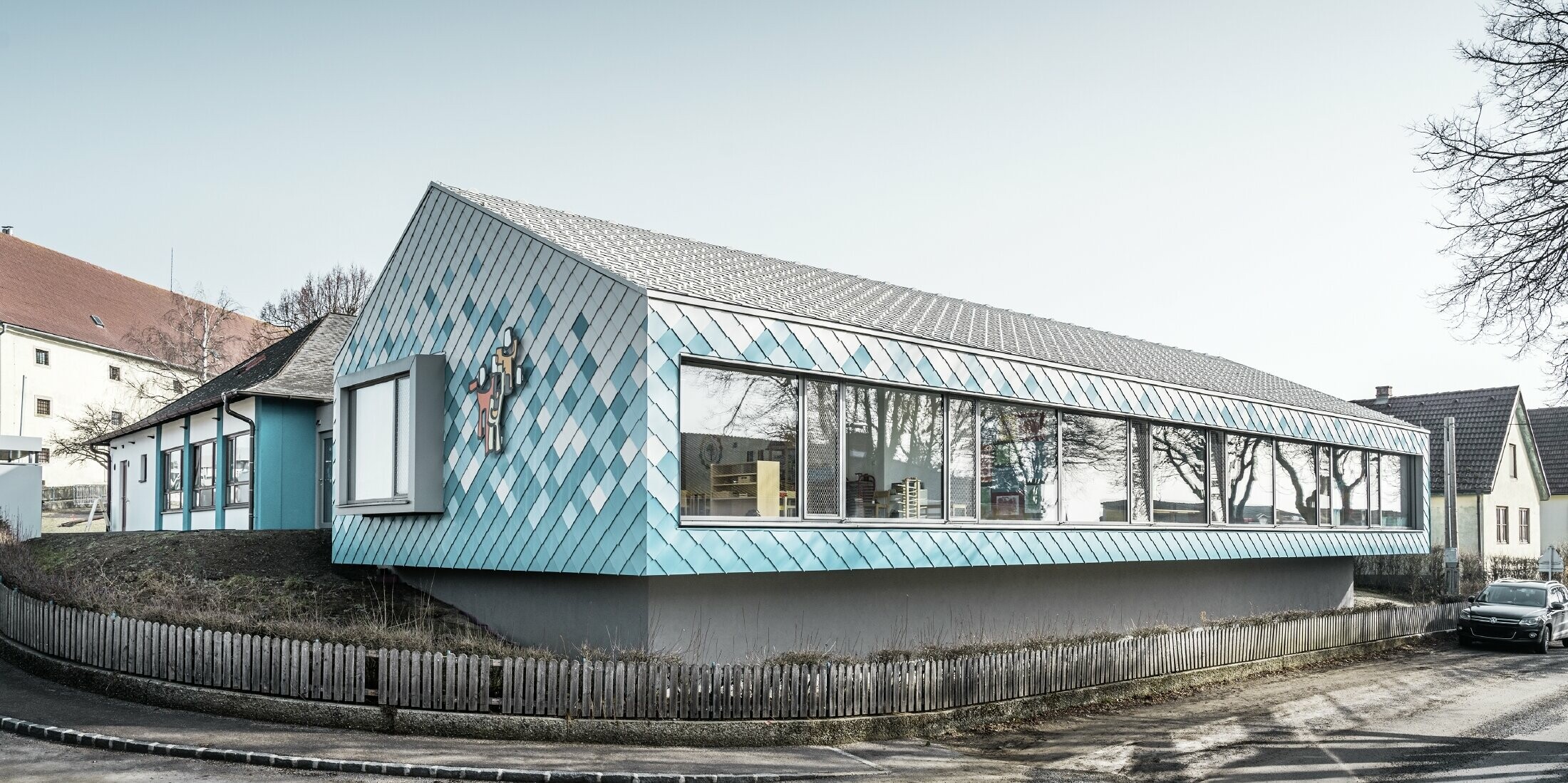 Ved børnehavens facadedesign blev der valgt PREFA-vægrombe i aluminium 29 i farverne ren hvid, lys blå og turkis. Disse blev lagt i et farveforløb (nederst blå, øverst hvid).