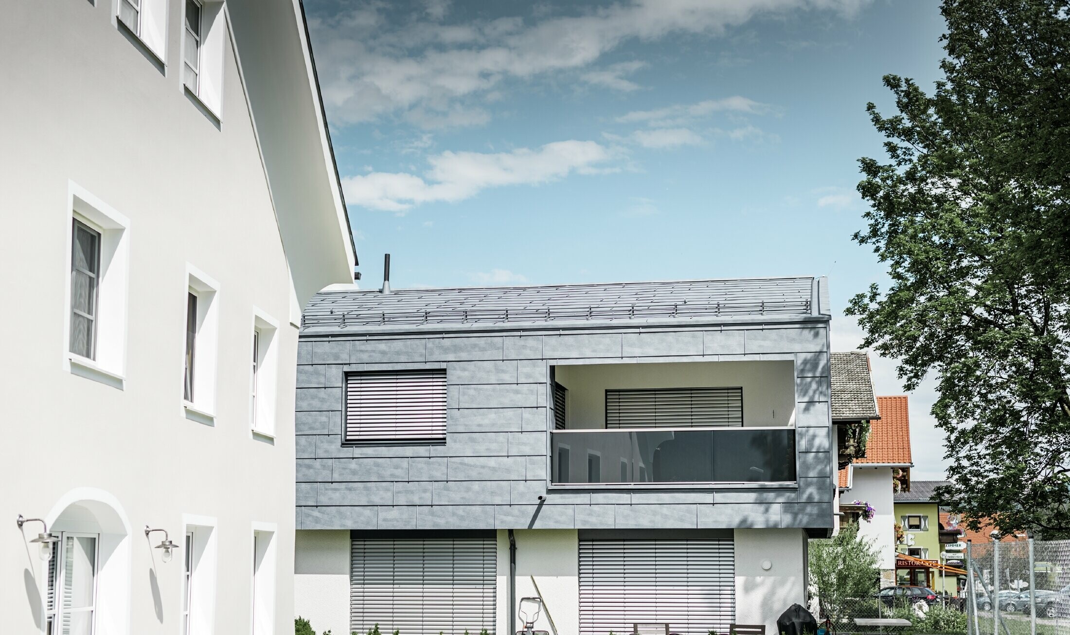 På beboelsesejendommen i Mieming er hele den øverste del af bygningen beklædt med PREFA facadepanel FX.12 i stengrå.