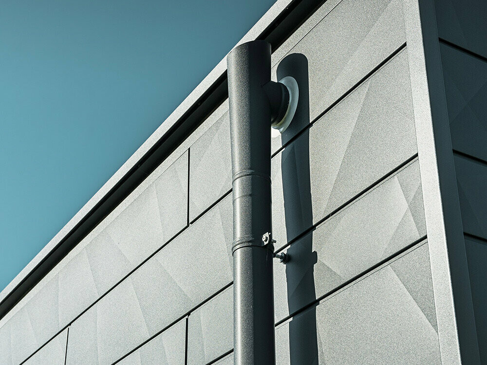 PREFA-afløbsrør med PREFA-udløb i P.10 antracit på en PREFA-Siding.X facade, ligeledes i P.10 antracit