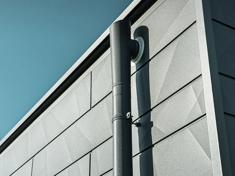 PREFA-afløbsrør med PREFA-udløb i P.10 antracit på en PREFA-Siding.X facade, ligeledes i P.10 antracit