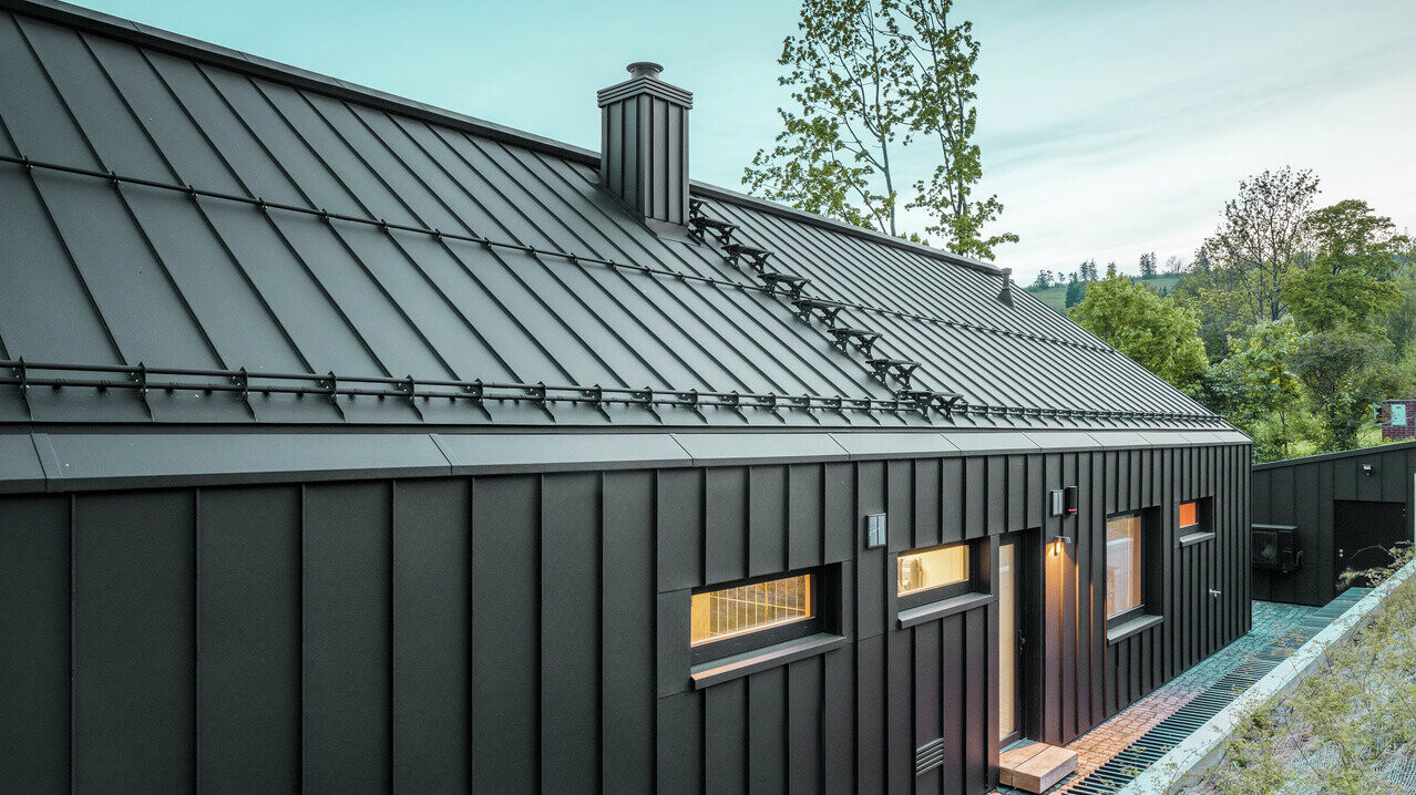 Das Bild zeigt ein Einfamilienhaus mit einem Dach und einer Fassade aus PREFALZ, Farbton P.10 Schwarz.