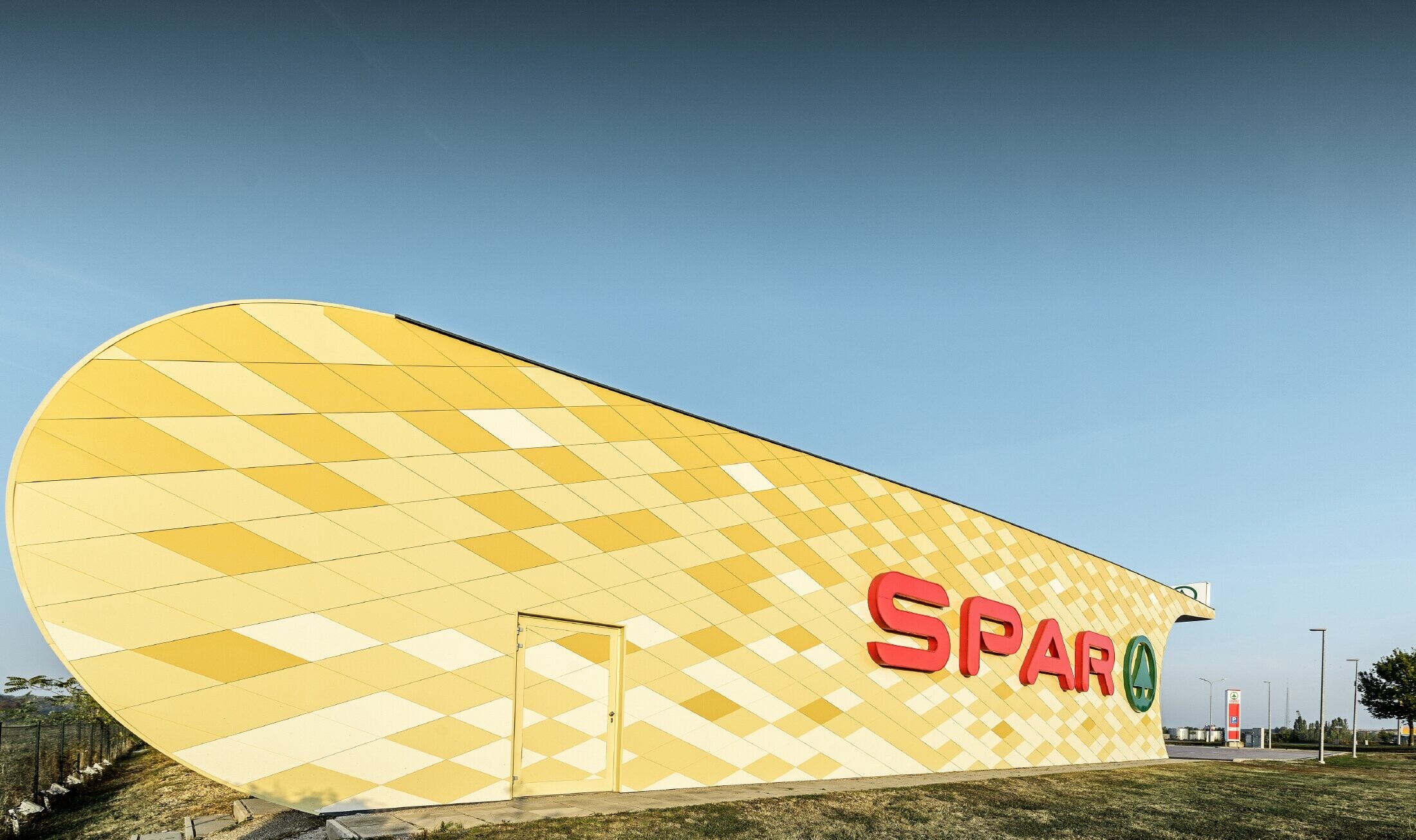 Spar-filial med en aluminiumfacade i gul-orange firkanter og Spar Logo