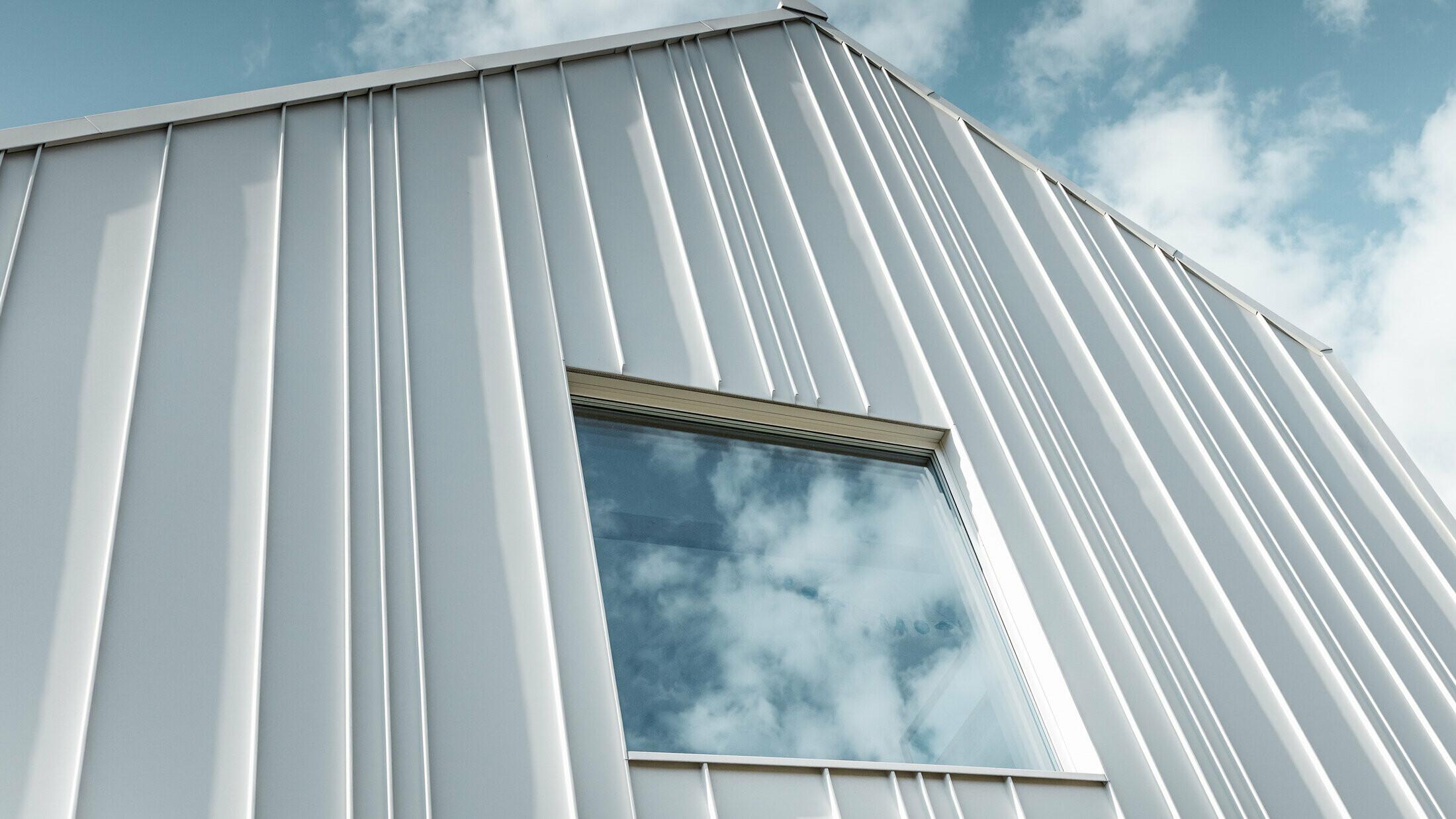 hvid PREFALZ som en vinkelstående fals på facaden med forskellige panelbredder og et vindue