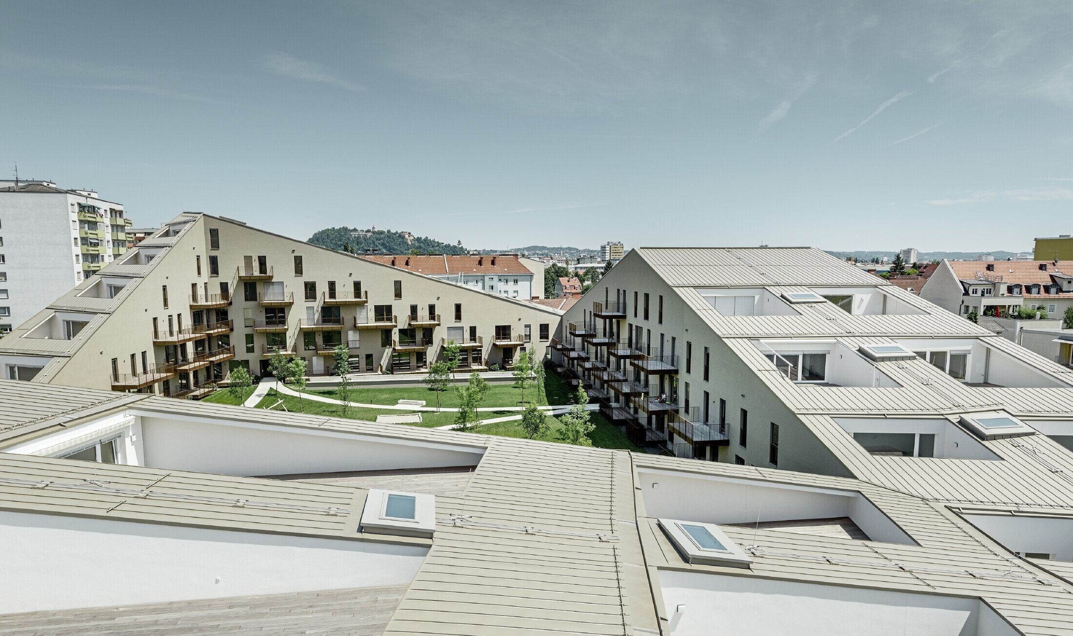 Langt boliganlæg i Graz med flade tagflader og integrerede terrasser og udstrakte vinduer med et Prefalztag i specialfarven bronzemetallic