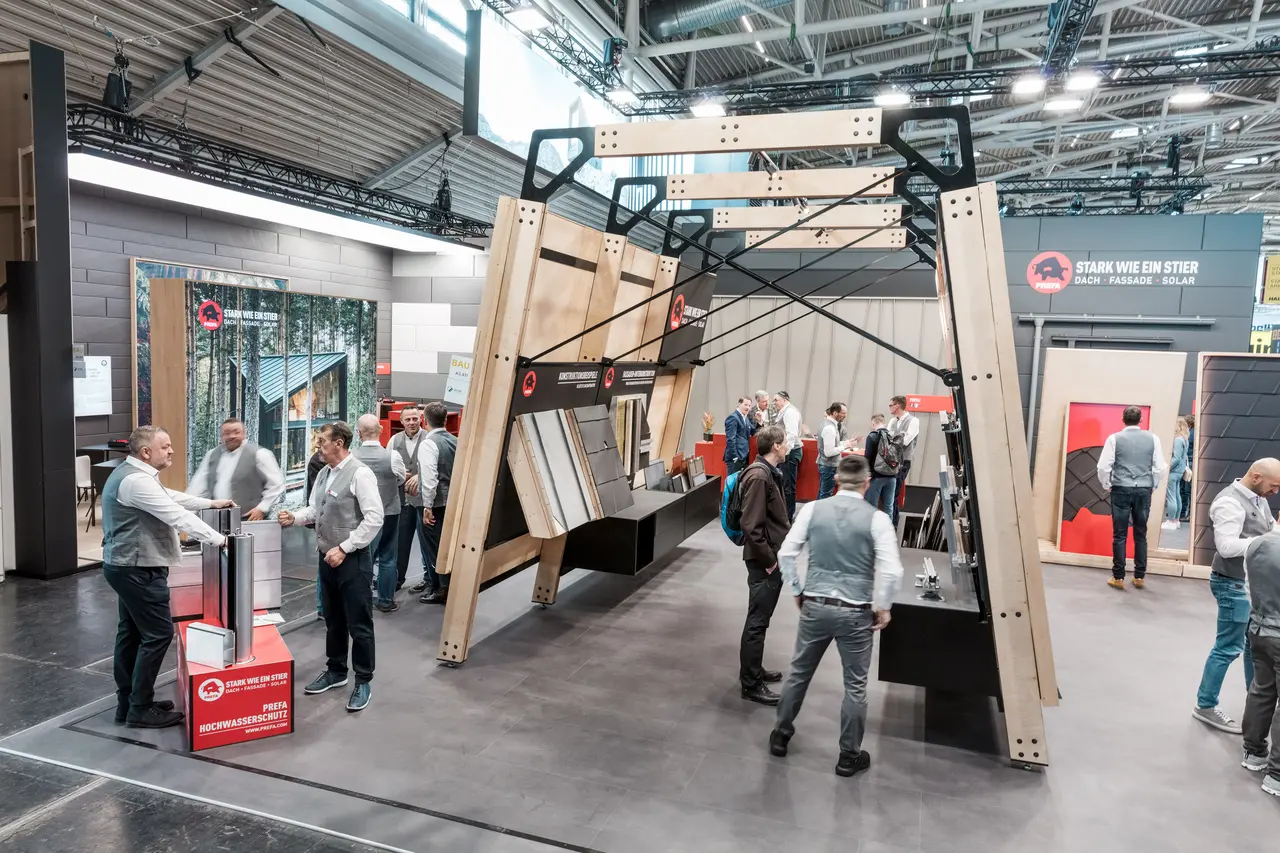 Den livlige PREFA-messestand med messevægge, hvor PREFA’s tag- og facadeprodukter i aluminium er udstillet.
