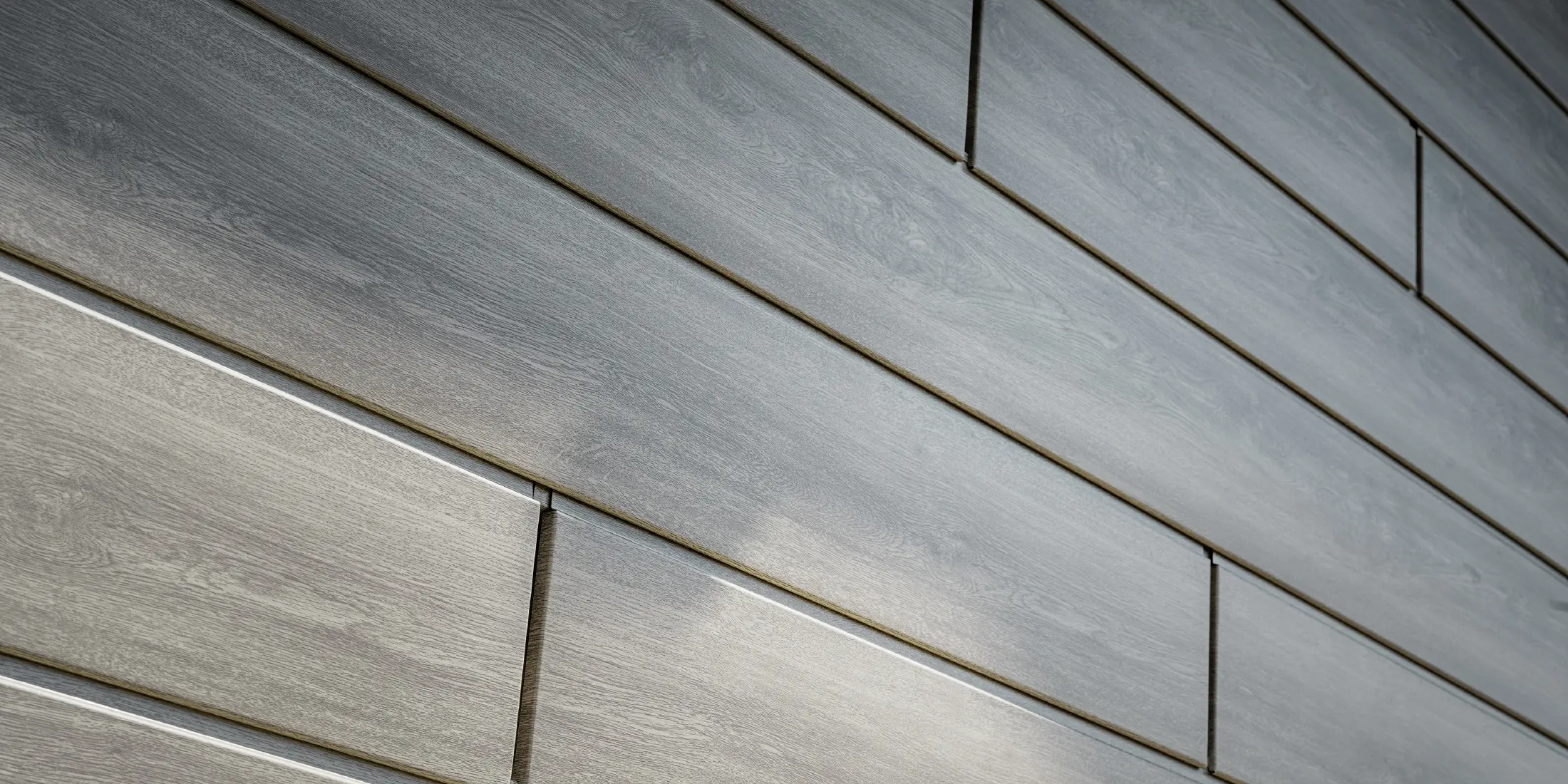 Nærbillede af PREFA Siding aluminiumsfacade, aluminiumspladerne er lagt horisontalt og har trælook – grå eg.