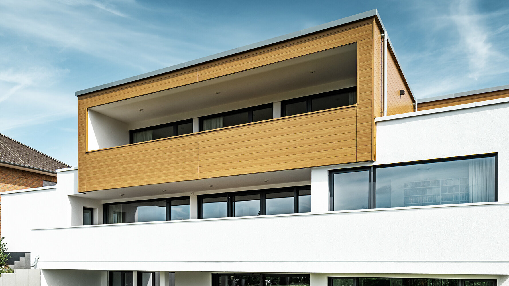 Moderne hus med karnap beklædt med PREFA Sidings i beige-grå.