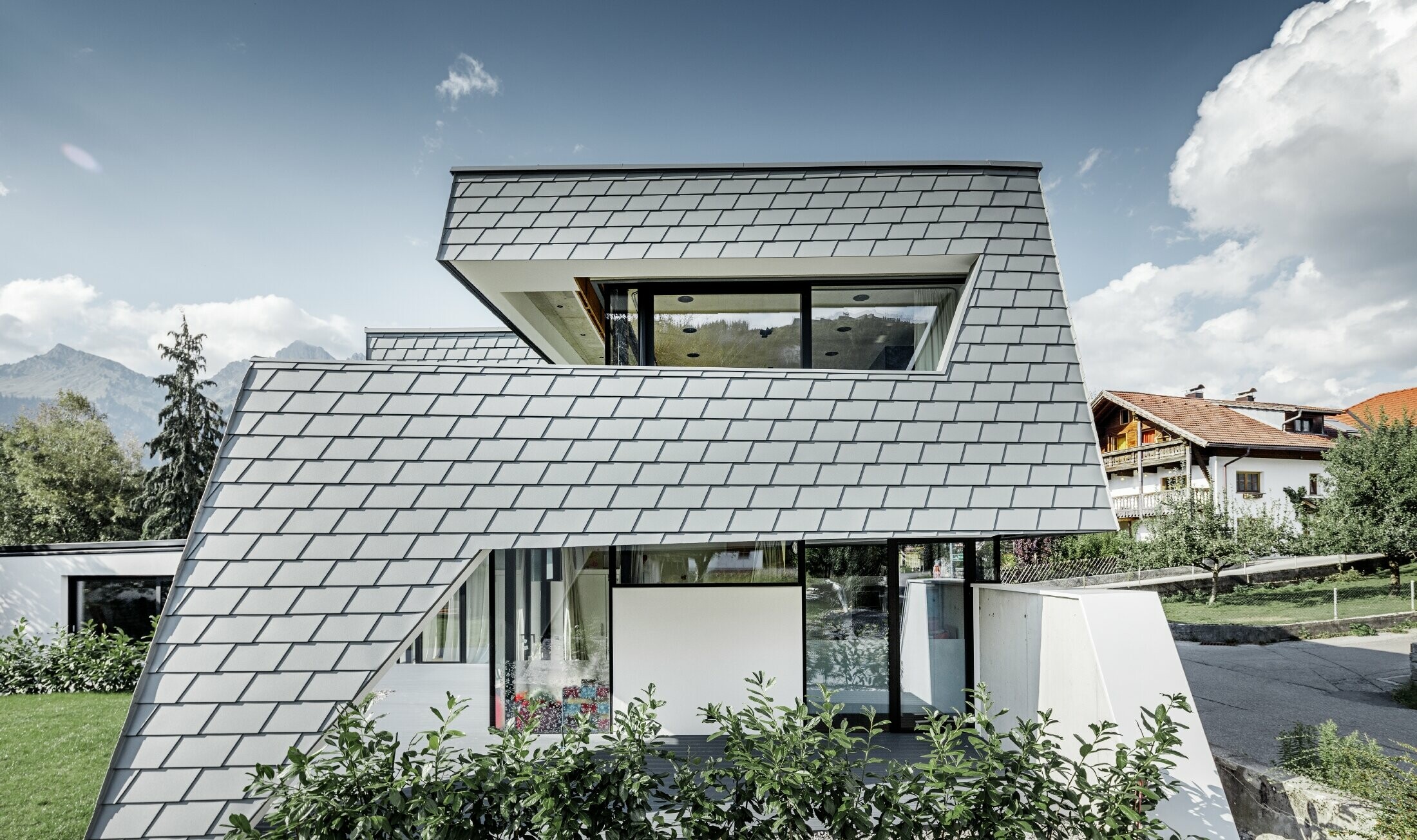 Moderne enfamiliehus med fladt tag, store vinduesflader og en vægspån-facade i lysegrå af aluminium fra PREFA