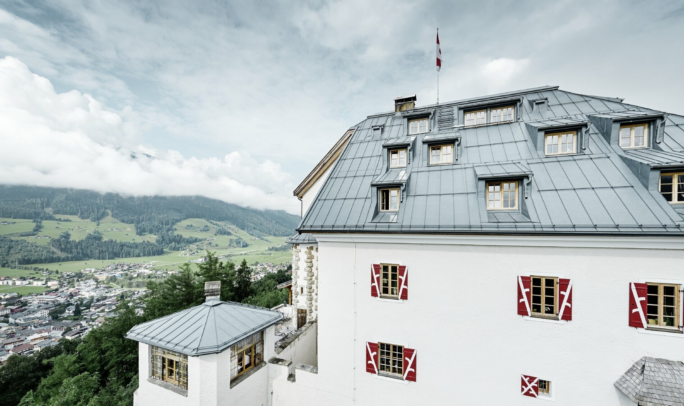 Schloss Mittersill omgivet af træer og bjerge med et nyt saneret Prefalz tag i stengrå