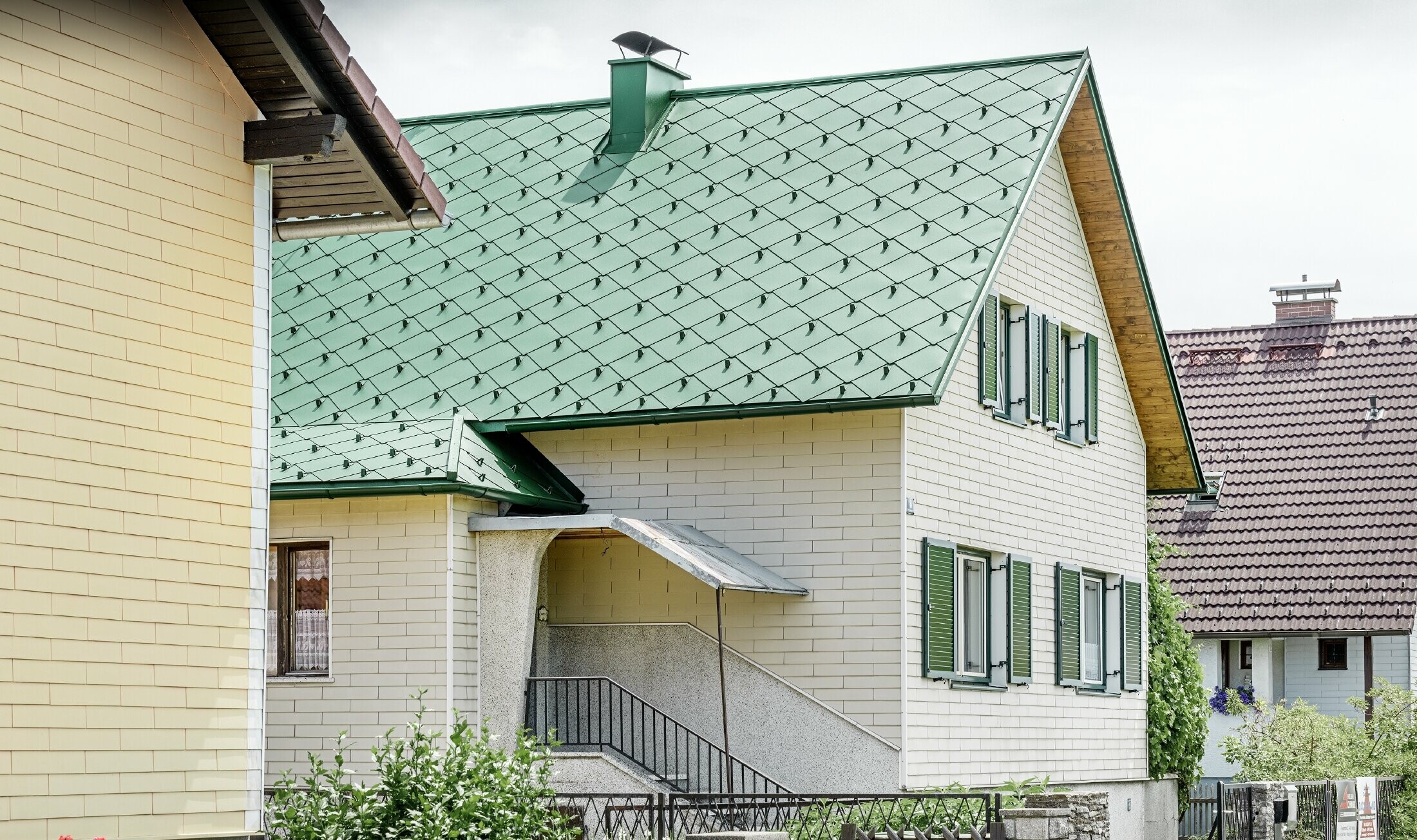 Klassisk enfamiliehus med sadeltag med en tagdækning af aluminium i mosgrøn med grønne vinduesskodder