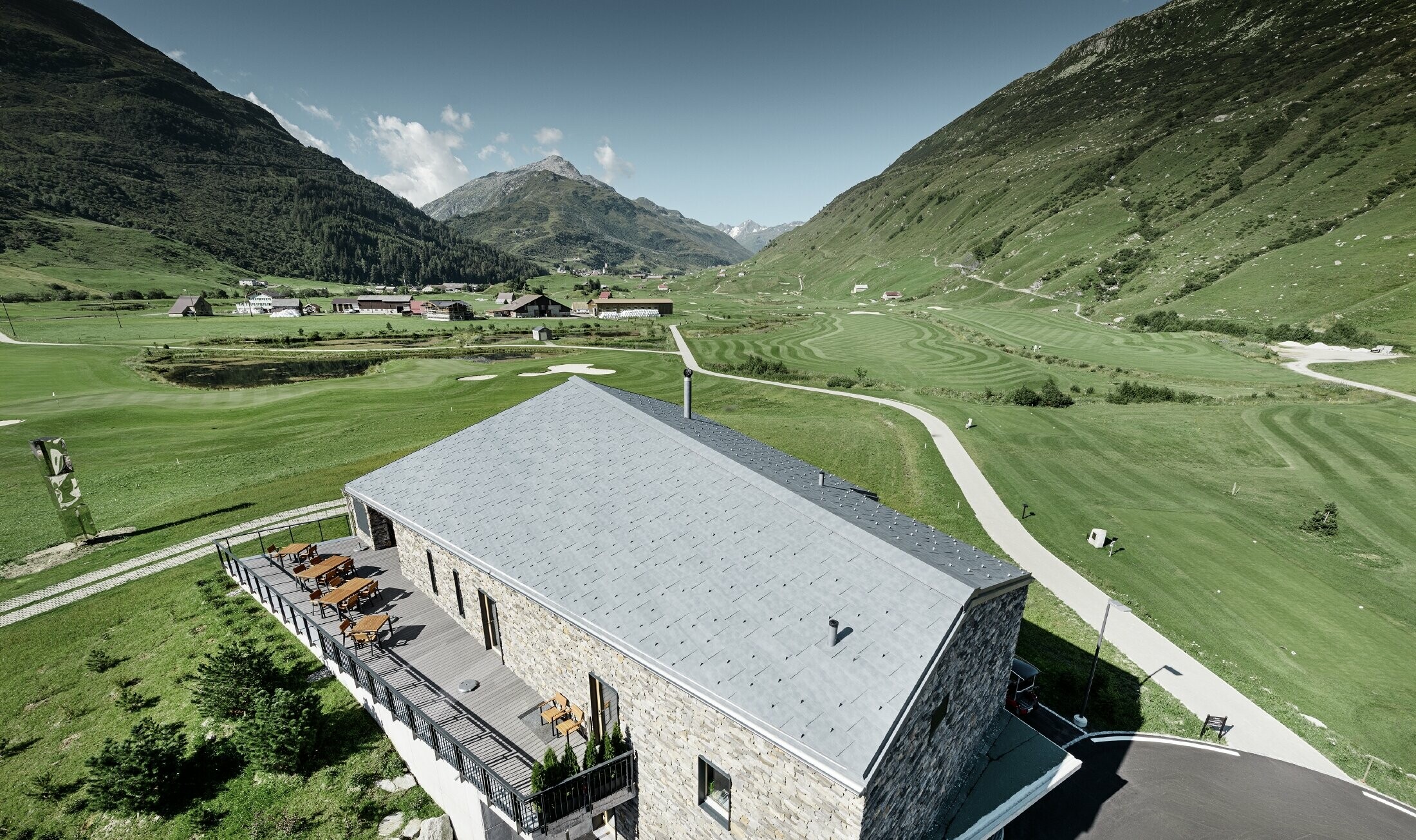 Moderne klubhus på golfbanen i Andermatt med stenfacade og PREFA tagpanel FX.12 i aluminium i stengrå