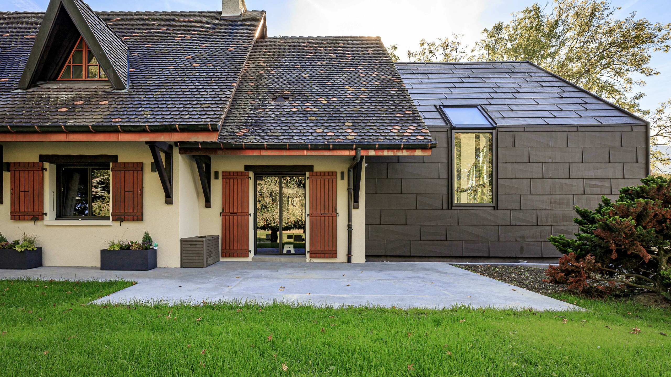 PREFA tag- og facadepaneler FX.12 i farven P.10 brun som et kontrastrigt designelement på tilbygningen til et enfamiliehus i Lully