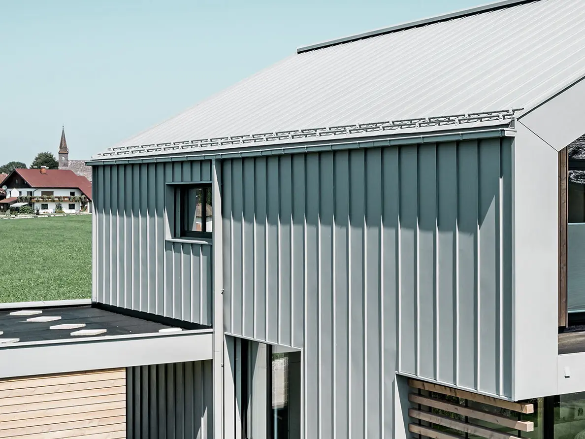 Enfamilieshus med sadeltag, med PREFALZ på tag og facade; Til tagafvanding anvendes firkantet PREFA-tagrende med PREFA-kvadratrør i specialfarven patinagrå.