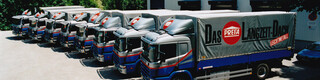 Otte tidligere PREFA lastbiler i blå og sølv med PREFA logo på rad og række 
