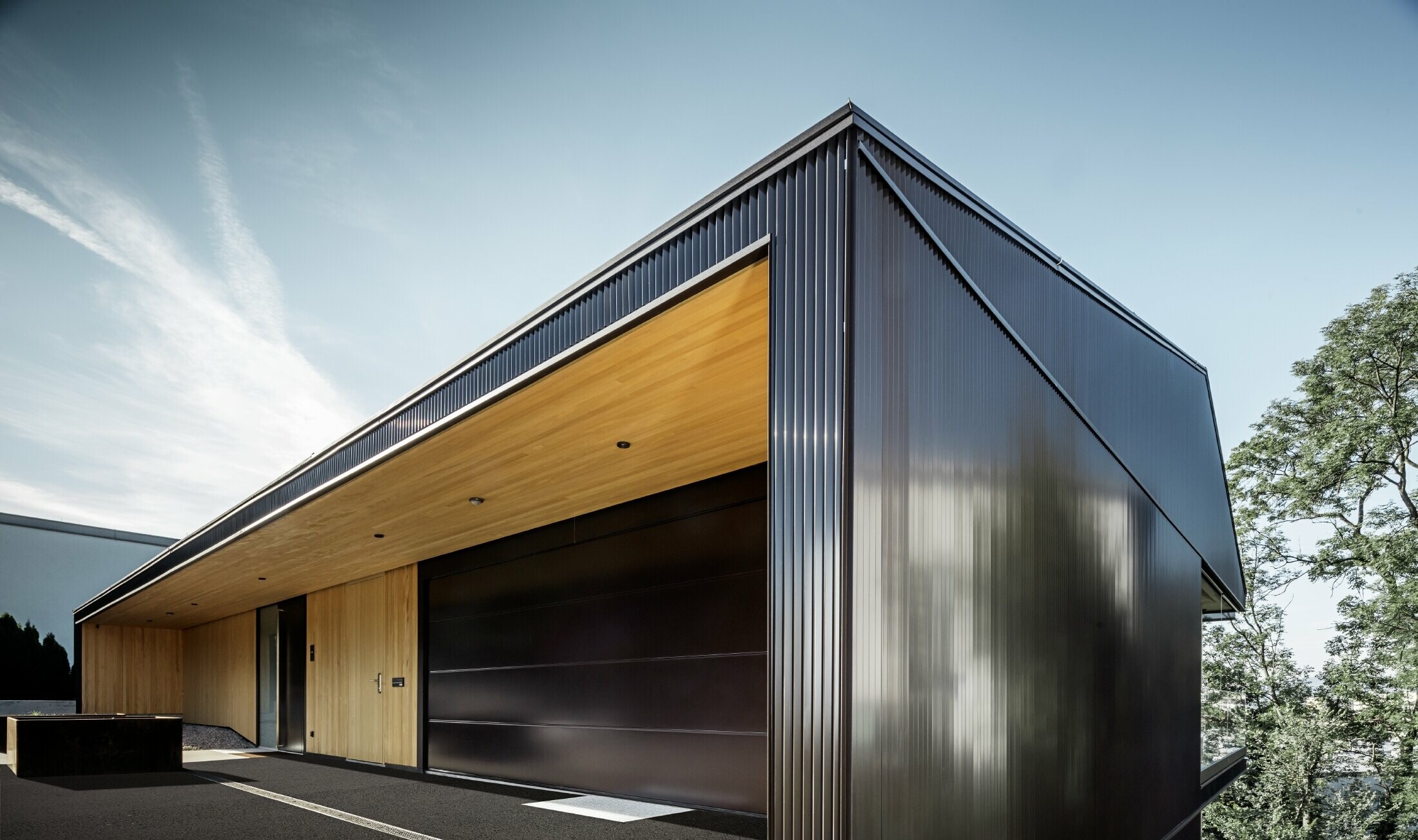 Garageindkørsel til et enfamilieshus, hvor facaden er beklædt med PREFAs takkede profil i mørkebrun. 