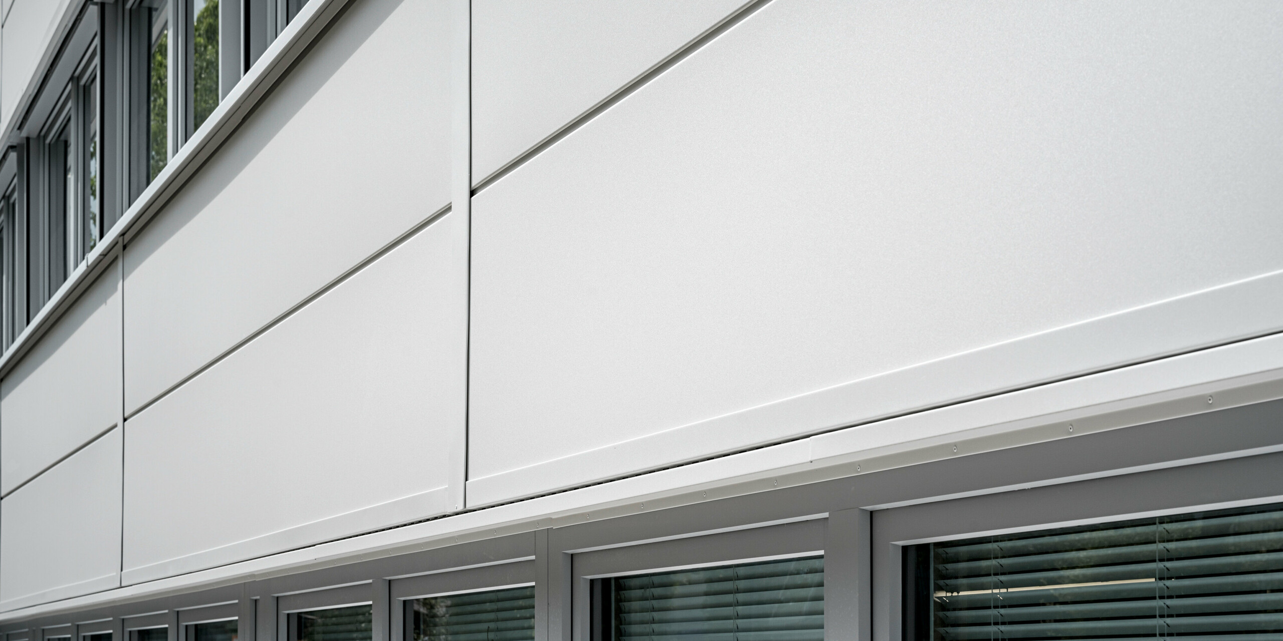 Großformatige PREFA Sidings umhüllen ein Firmengebäude in Oberschleißheim (Deutschland). Die extrabreiten Fassadenelemente aus Aluminium sind in der Farbe Prefaweiß gehalten.