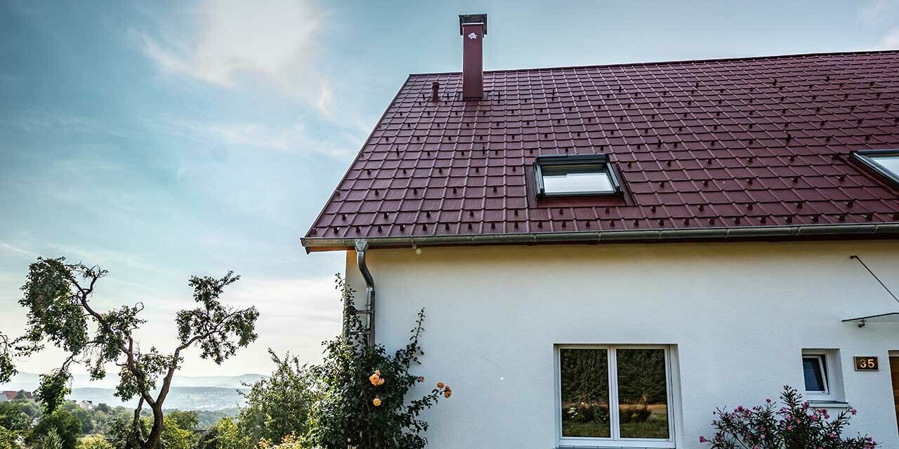Lille hus på landet, nyrenoveret tag med PREFA-tagplade i oxidrød, tagvinduer og skorstensinddækning.
