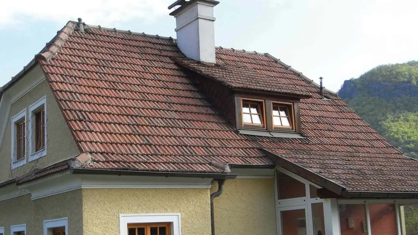 Gammelt enfamilieshus, før tagrenovering, med tegltag og ru, gul pudset facade