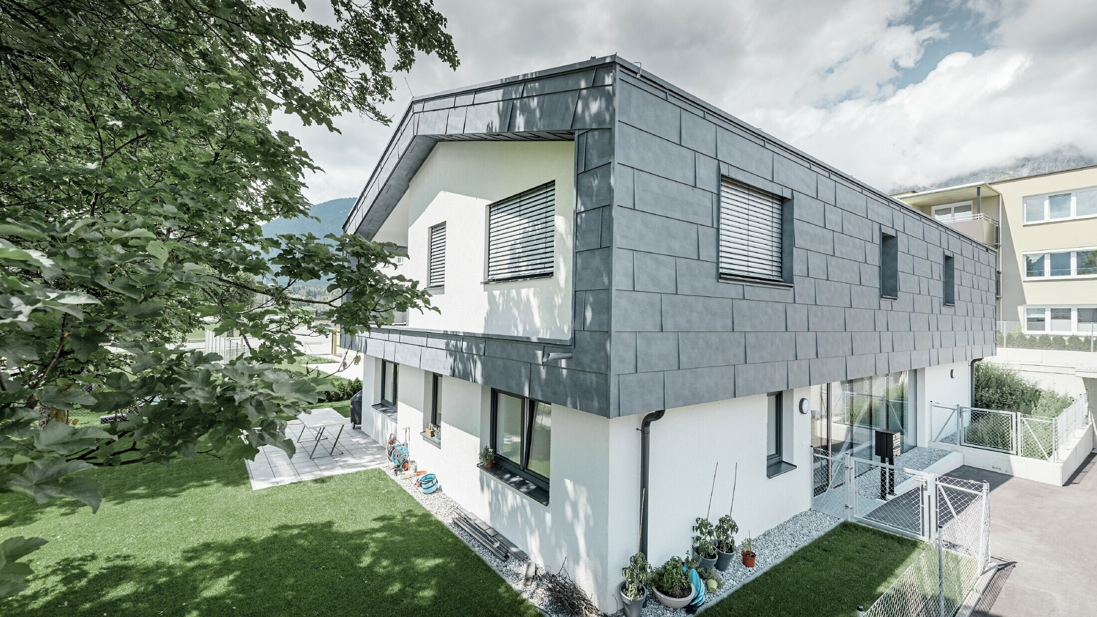 Moderne udvidelse af en beboelsesejendom med fladt sadeltag og uden tagudhæng. Facadebeklædningen er udført med PREFA facadepanel FX.12 i stengrå.