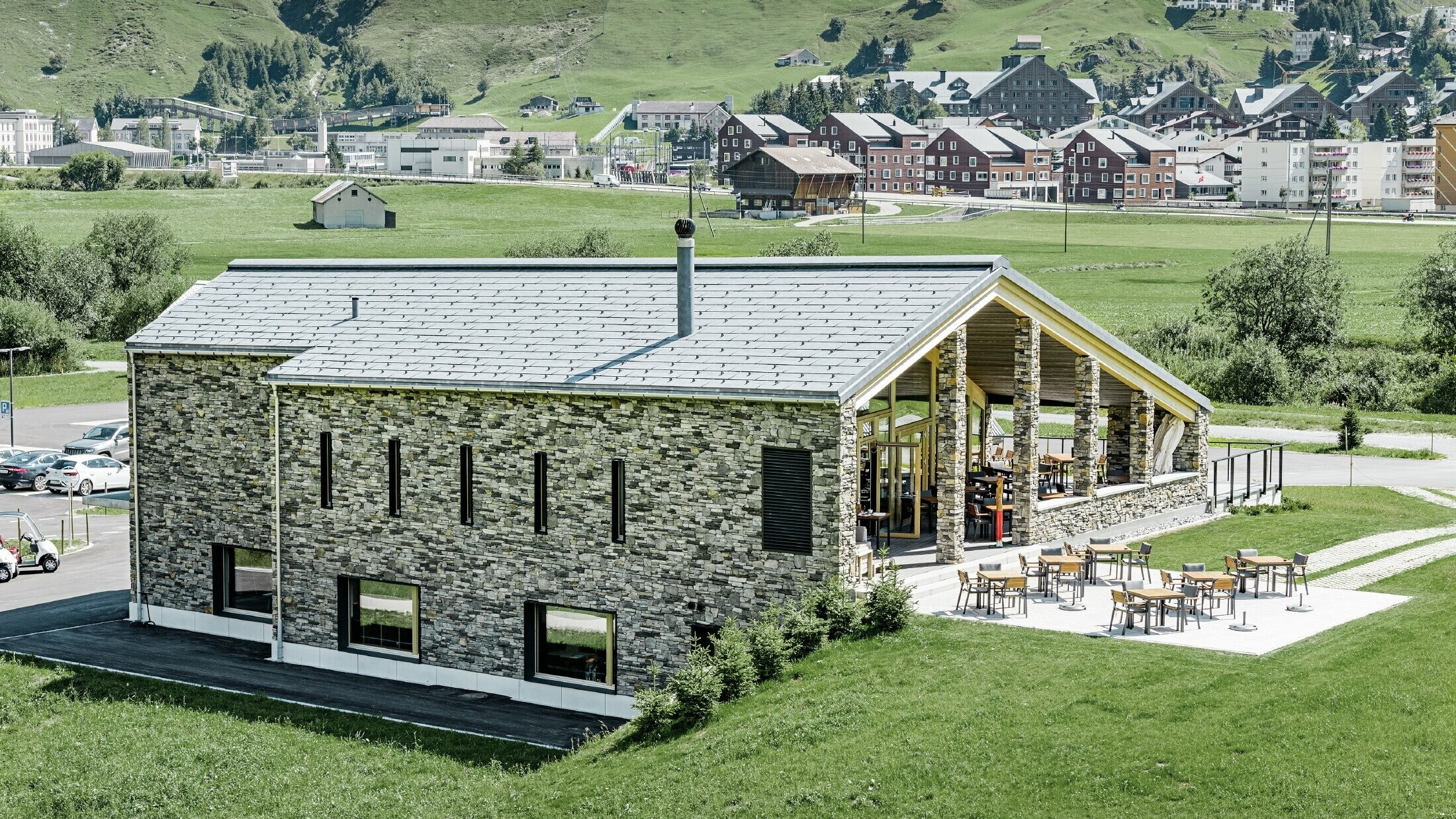 Moderne klubhus på golfbanen i Andermatt med stenfacade og PREFA tagpanel FX.12 i aluminium i stengrå
