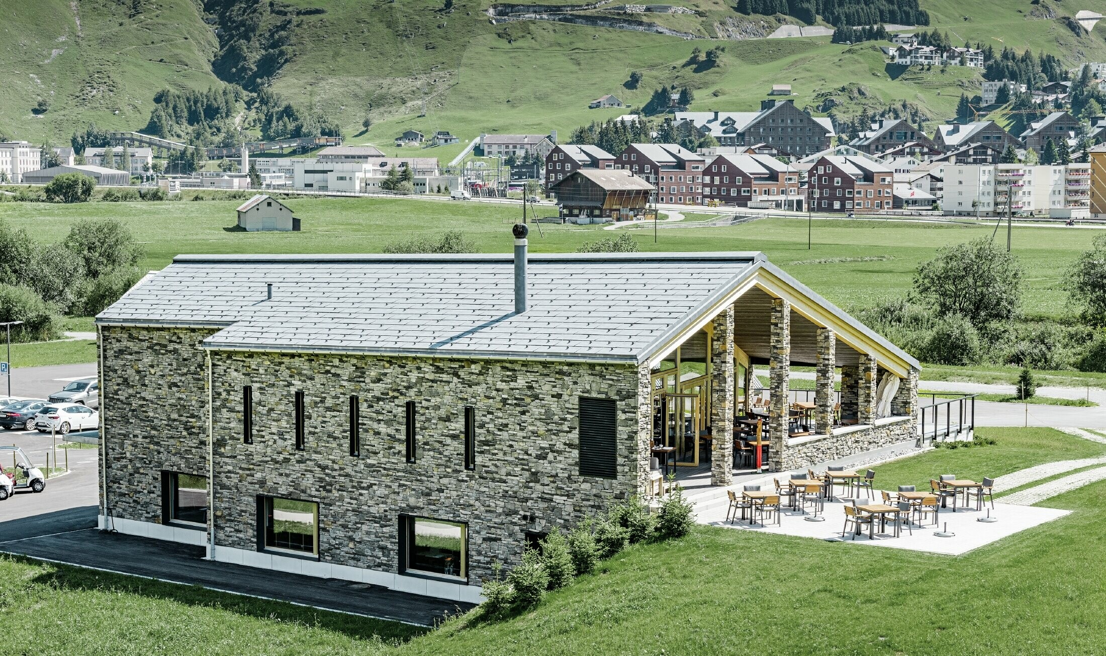 Moderne klubhus på golfbanen i Andermatt med stenfacade og PREFA tagpanel FX.12 i aluminium i stengrå