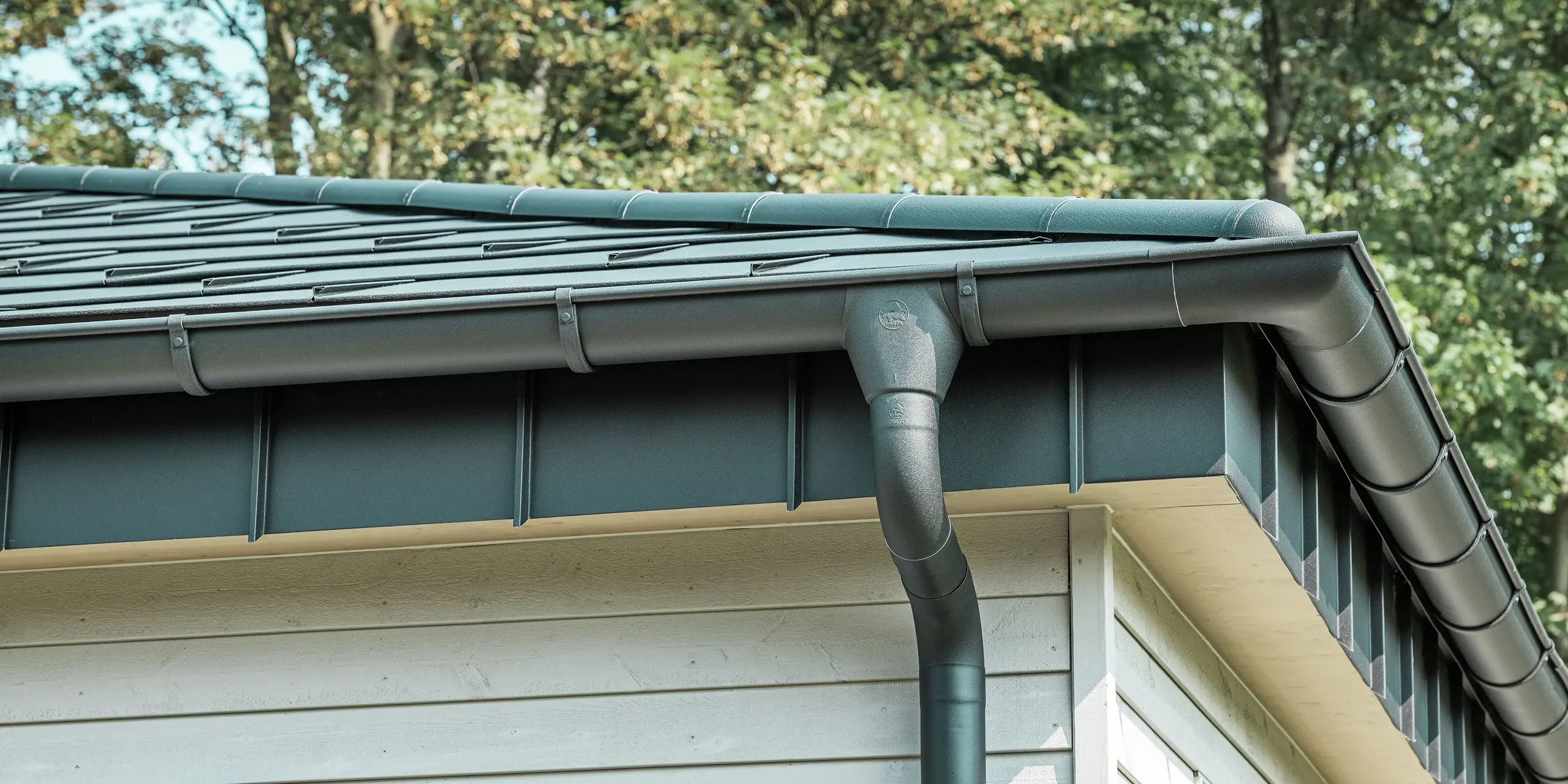 Detalje af PREFA tagafvanding på en bungalow i Rommerskirchen. Den høje kvalitet af fodrenden og nedløbsrøret i P.10 sort sikrer en sikker tagafvanding ved regn. De holdbare PREFA aluminiumsprodukter kombinerer funktionalitet med et moderne, elegant design.