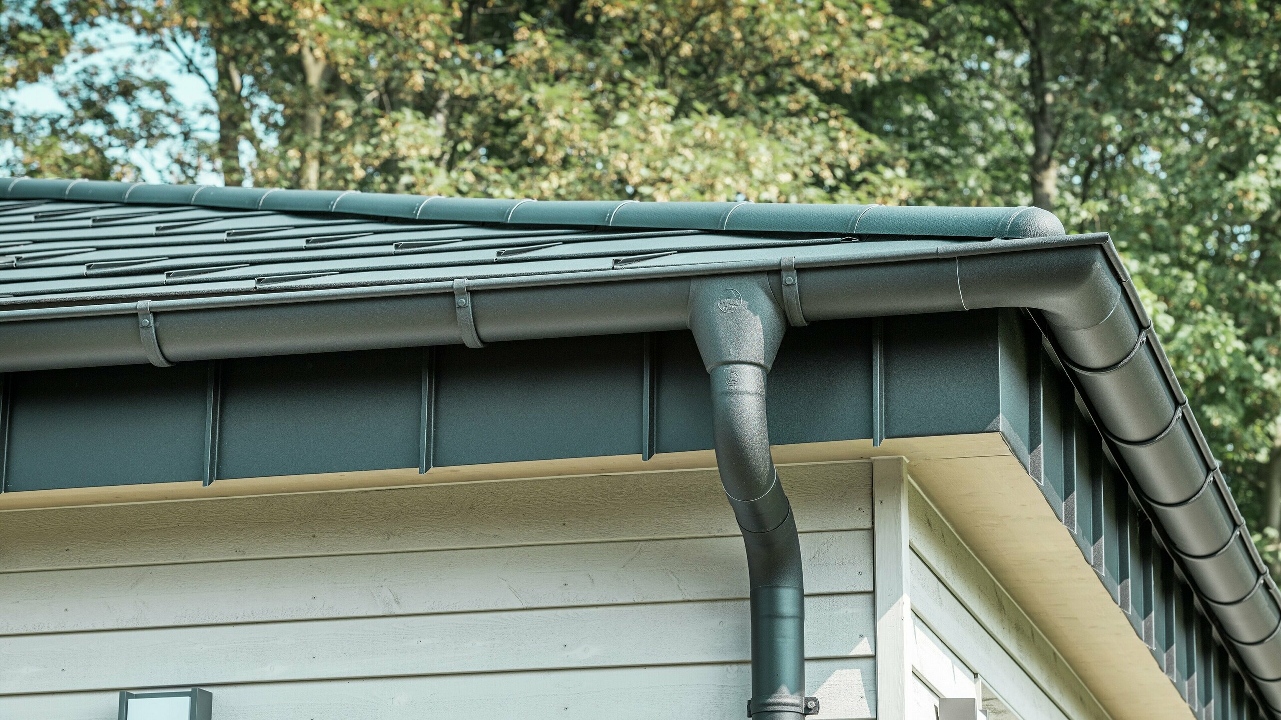 Detalje af PREFA tagafvanding på en bungalow i Rommerskirchen. Den høje kvalitet af fodrenden og nedløbsrøret i P.10 sort sikrer en sikker tagafvanding ved regn. De holdbare PREFA aluminiumsprodukter kombinerer funktionalitet med et moderne, elegant design.