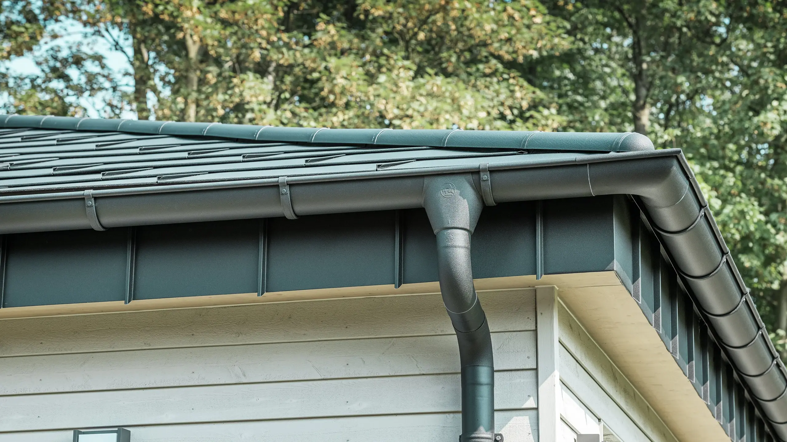 Detalje af PREFA tagafvanding på en bungalow i Rommerskirchen. Den høje kvalitet af fodrenden og nedløbsrøret i P.10 sort sikrer en sikker tagafvanding ved regn. De holdbare PREFA aluminiumsprodukter kombinerer funktionalitet med et moderne, elegant design.