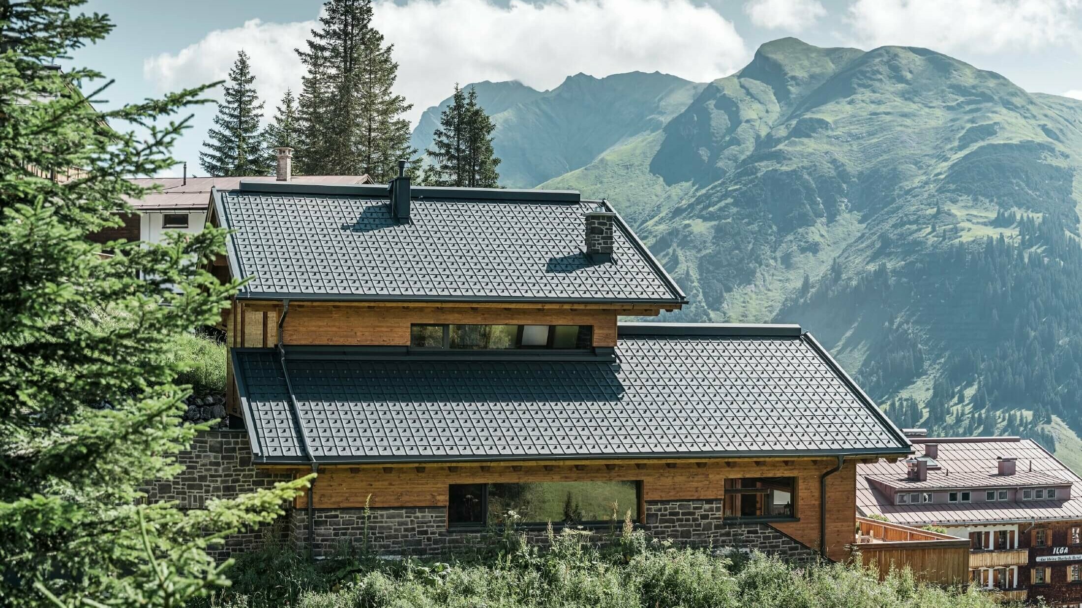 Et hus i alpine omgivelser med tagdækning af antracitfarvede PREFA-tagplader