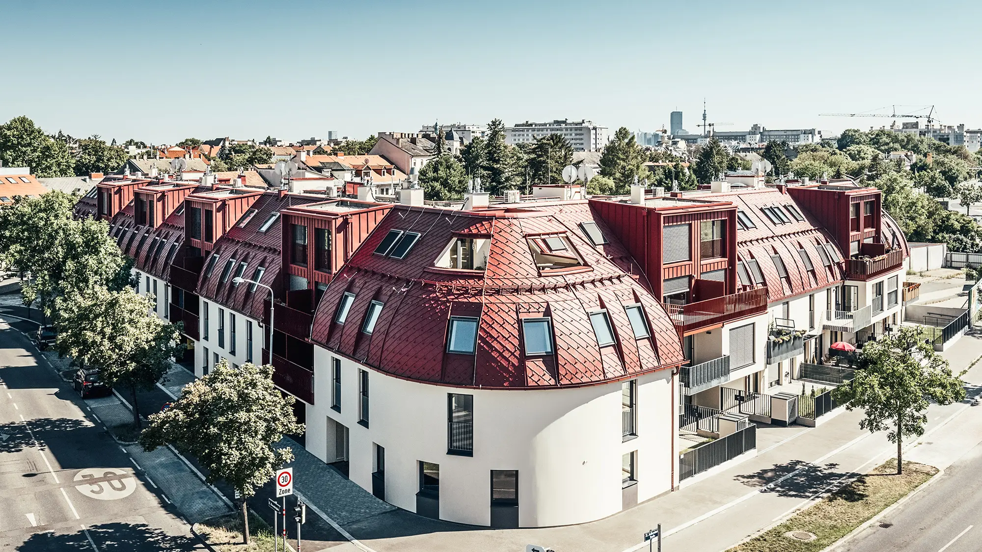 Gadeudsigt over boligkomplekset Schöneck 13 og det afrundede taglandskab, designet af arkitektfirmaet schneider+schumacher.