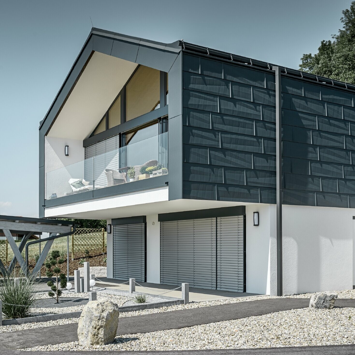 Moderne flerfamilieshus med stor vinduesfront, tag og facade blev beklædt med tag- og facadepanel FX.12 i antracit fra PREFA