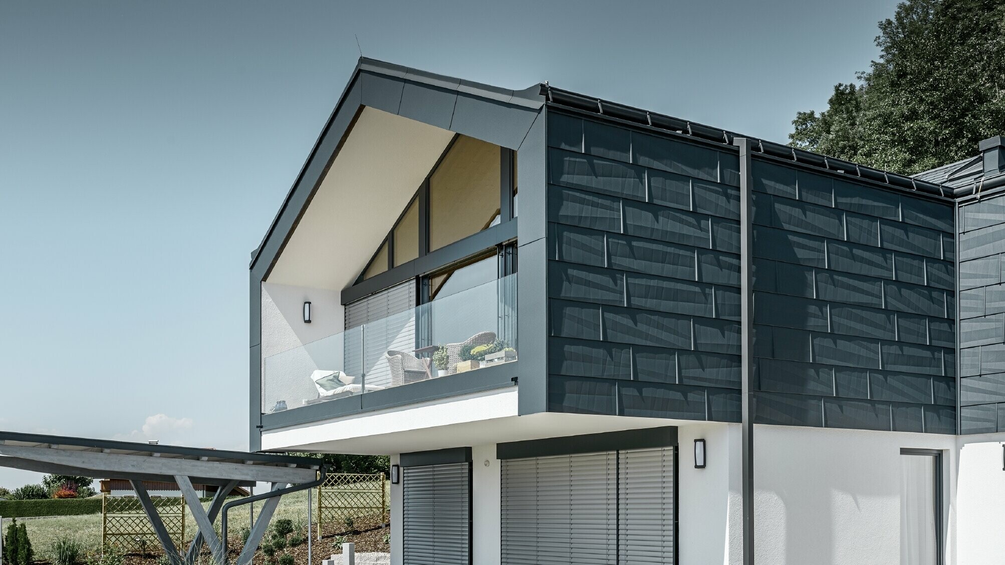 Moderne flerfamilieshus med stor vinduesfront, tag og facade blev beklædt med tag- og facadepanel FX.12 i antracit fra PREFA
