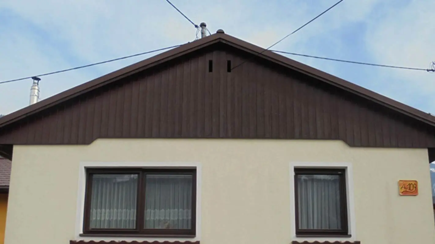 Gavl før facaderenovering med PREFA sidings, gul gipsfacade og forvitret træ