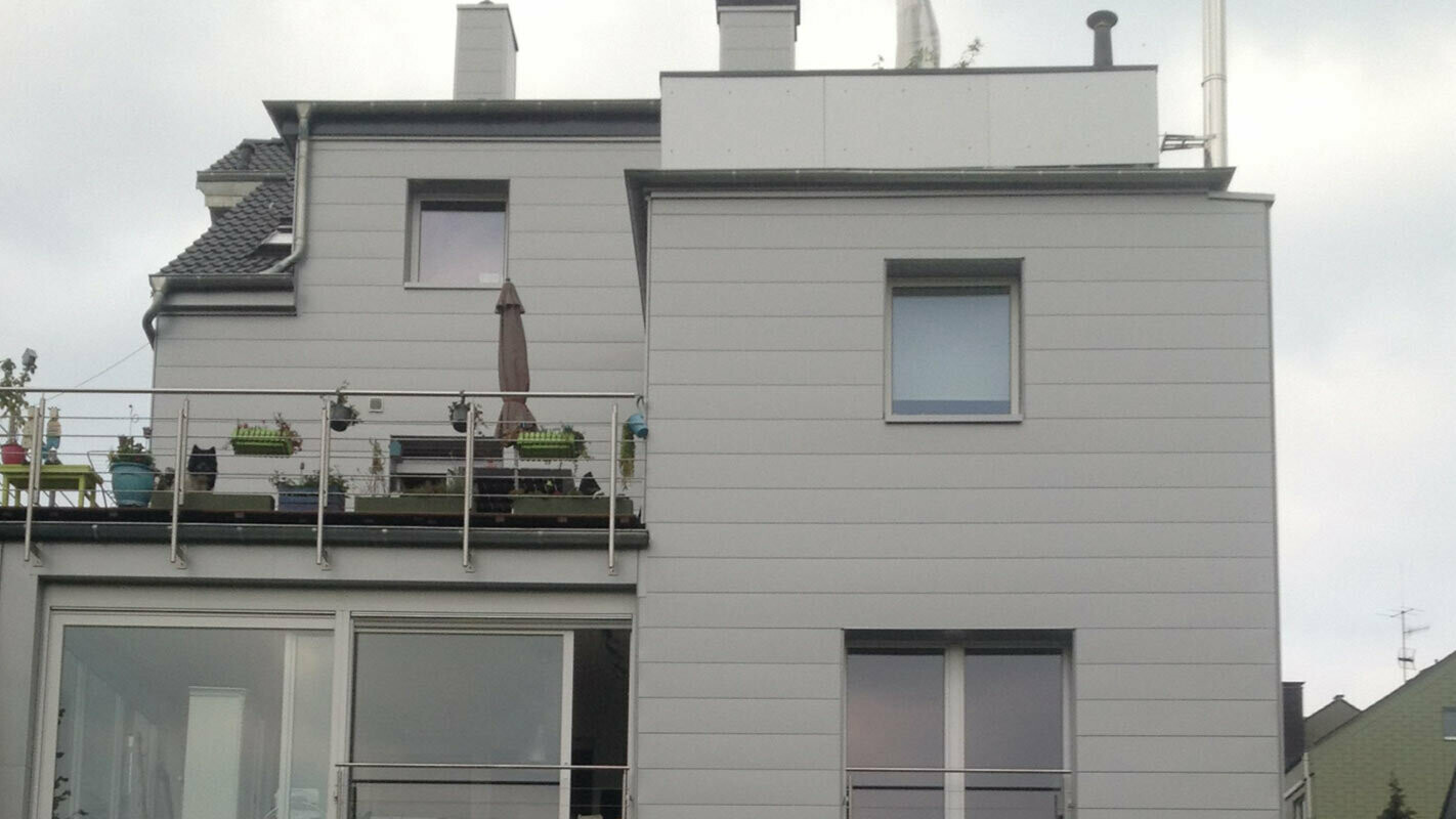 Boligblok med fladt tag og terrasse med nyrenoveret facade med PREFA sidings