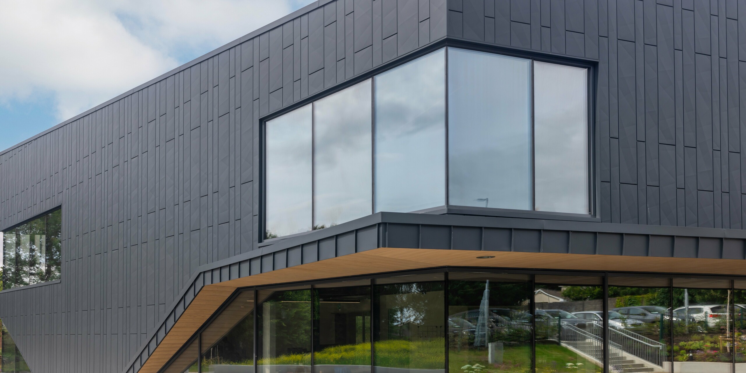Detailansicht der modernen Fassade des CREW-Gebäudes in Galway, Irland, gestaltet mit PREFA Siding.X Fassadenpaneelen und PREFALZ in der Farbe P.10 Anthrazit. Das markante Eckfenster unterstreicht die klare Linienführung und die innovative Architektur des Bauwerks. Die anthrazitfarbene Aluminiumverkleidung verleiht dem Objekt eine zeitlose Eleganz und demonstriert die hohe Qualität der PREFA Aluminiumprodukte.